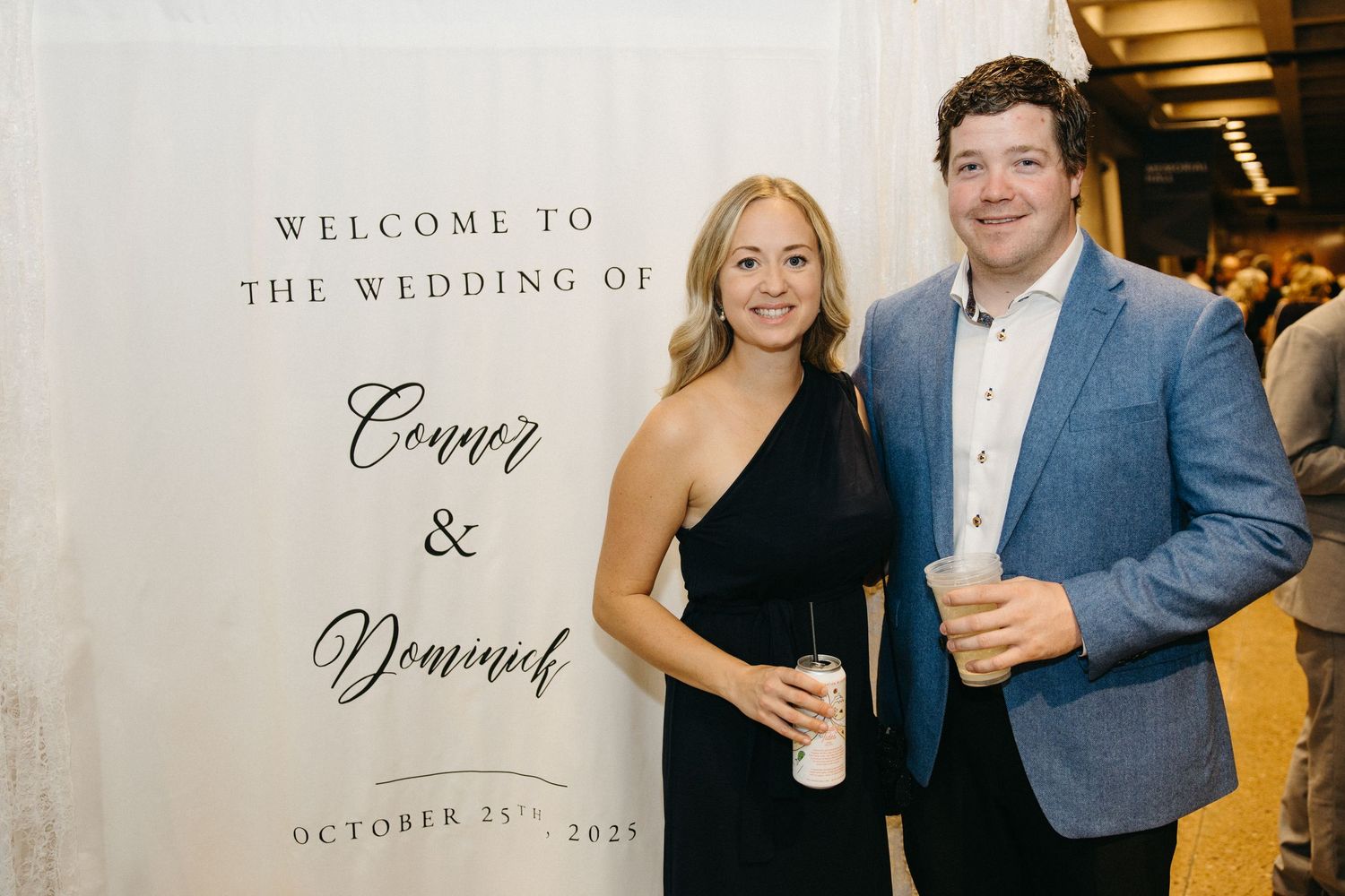 Welcome sign and guests posing at a formal wedding celebration.