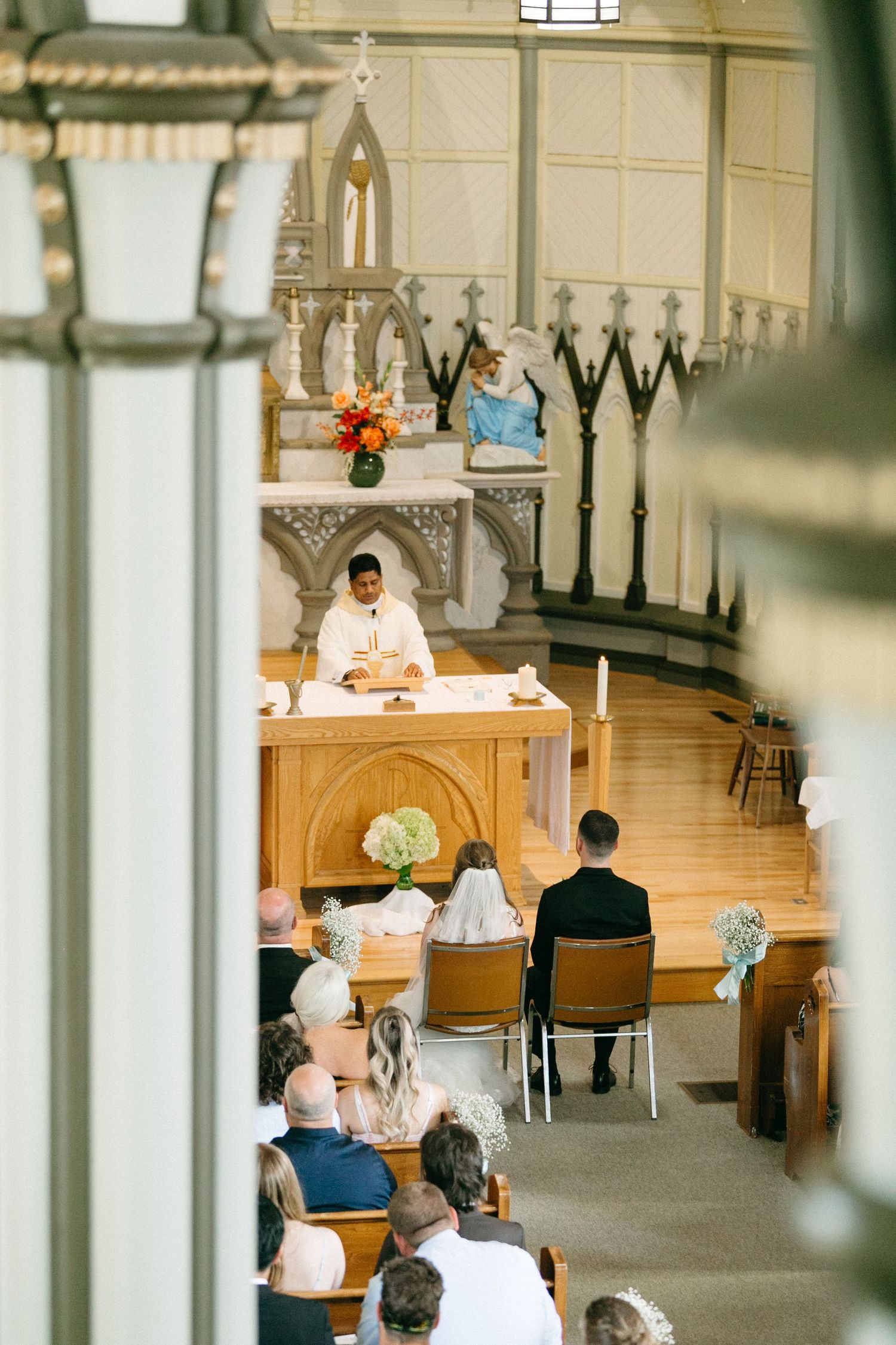 Religious ceremony taking place inside a traditional church with ornate wooden altar and candlesticks.