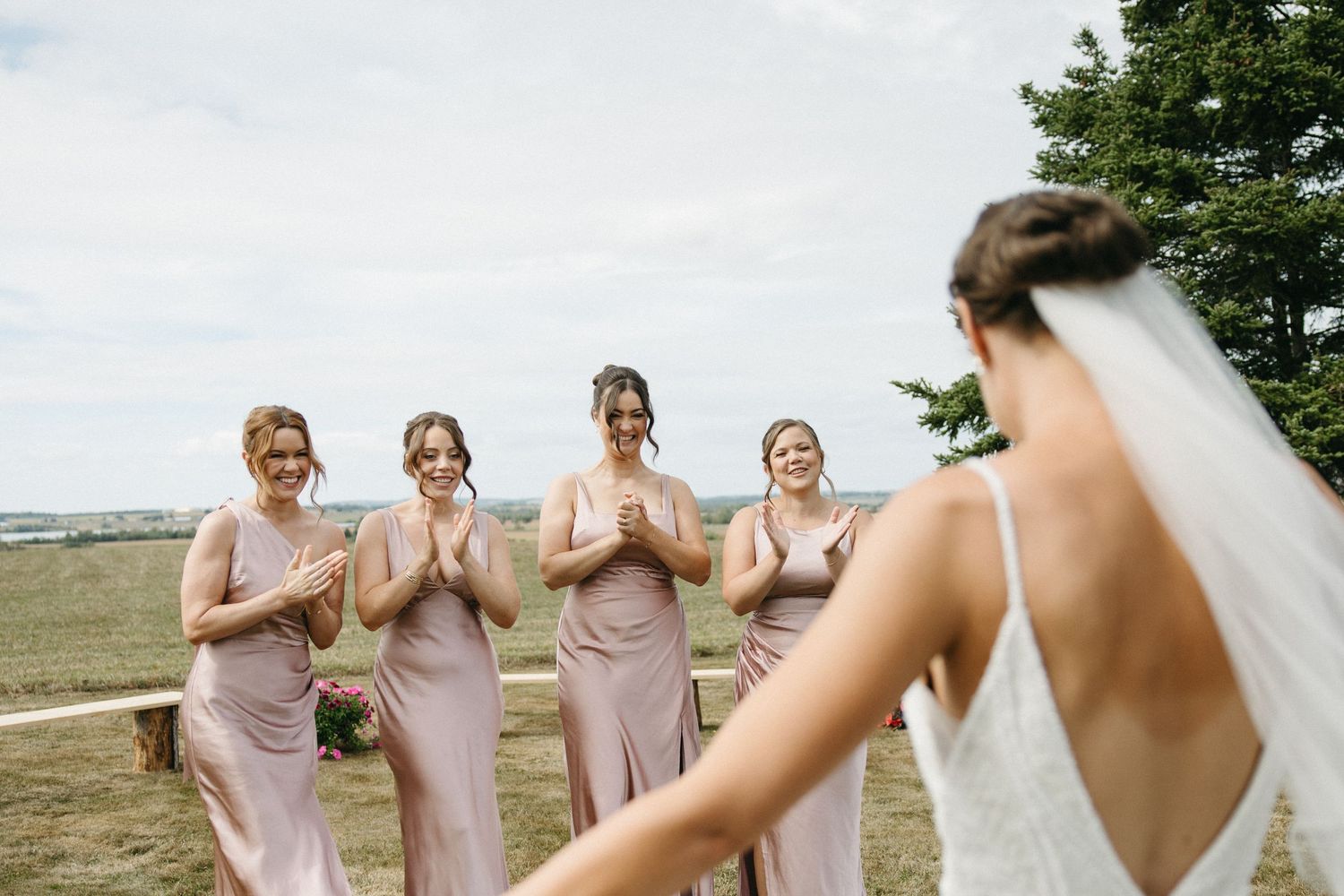 Bridesmaids in blush pink dresses celebrating outdoors.