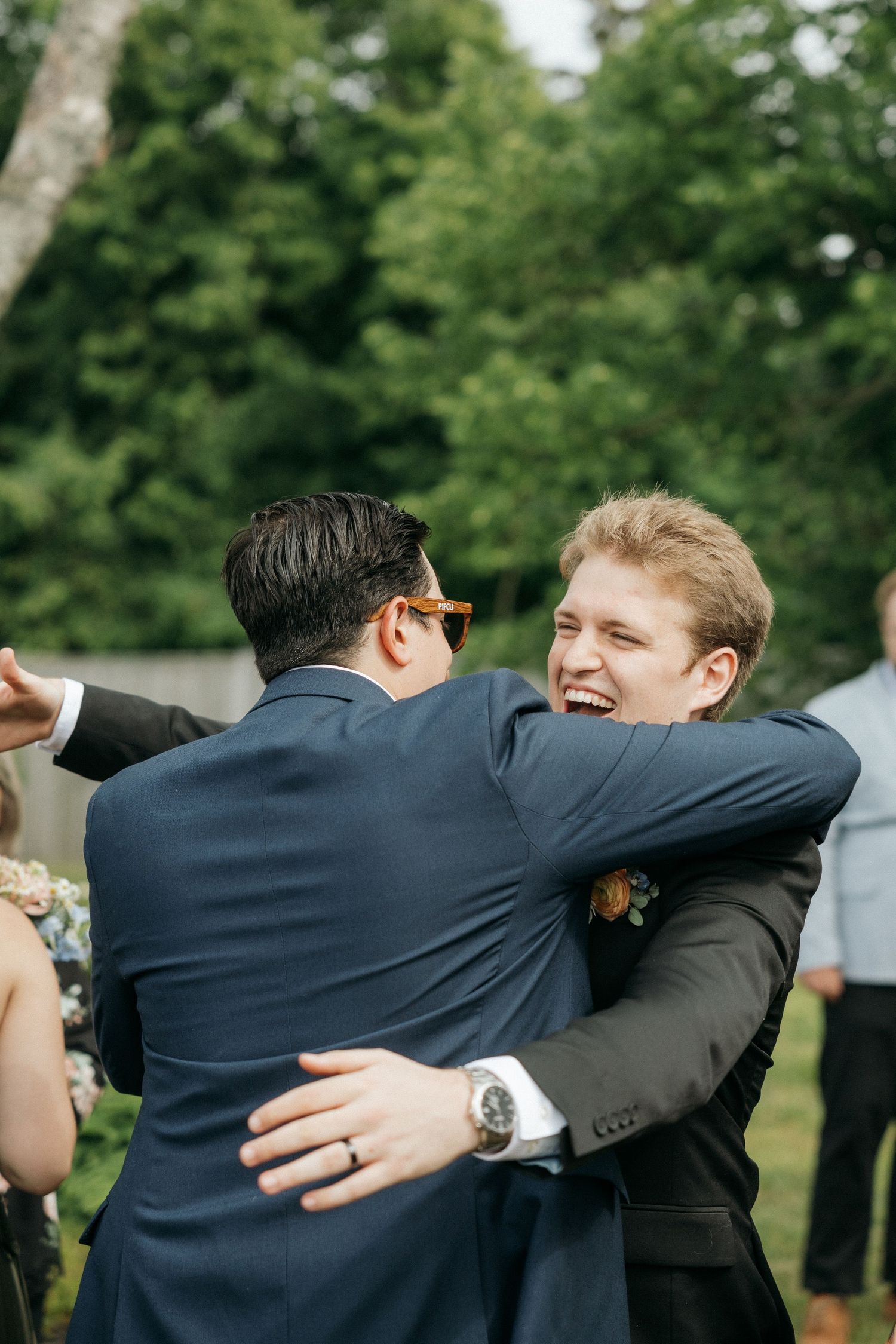 Groomsmen share enthusiastic group hugs during wedding celebrations.