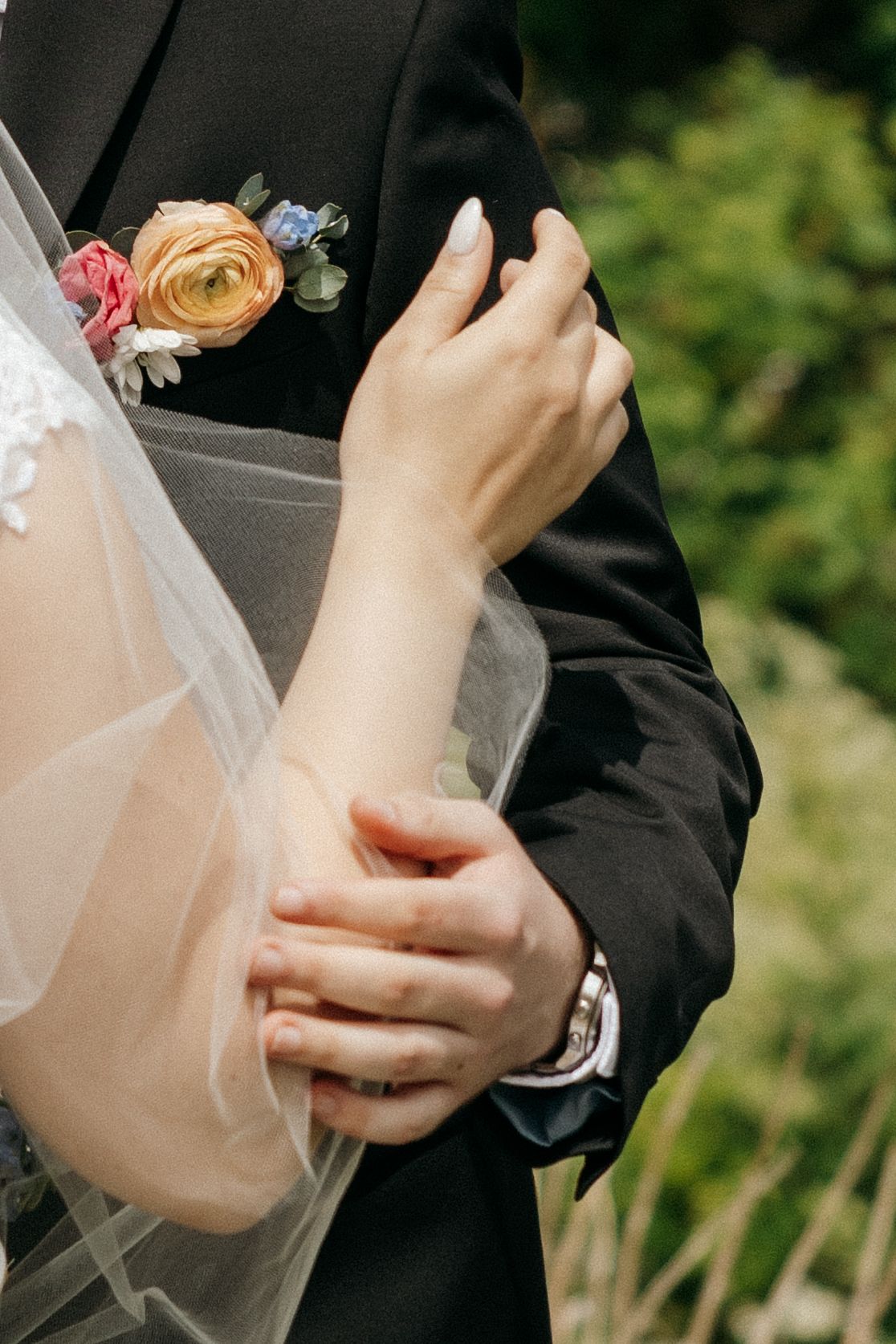 Close-up details of wedding attire and floral accessories during an outdoor ceremony.