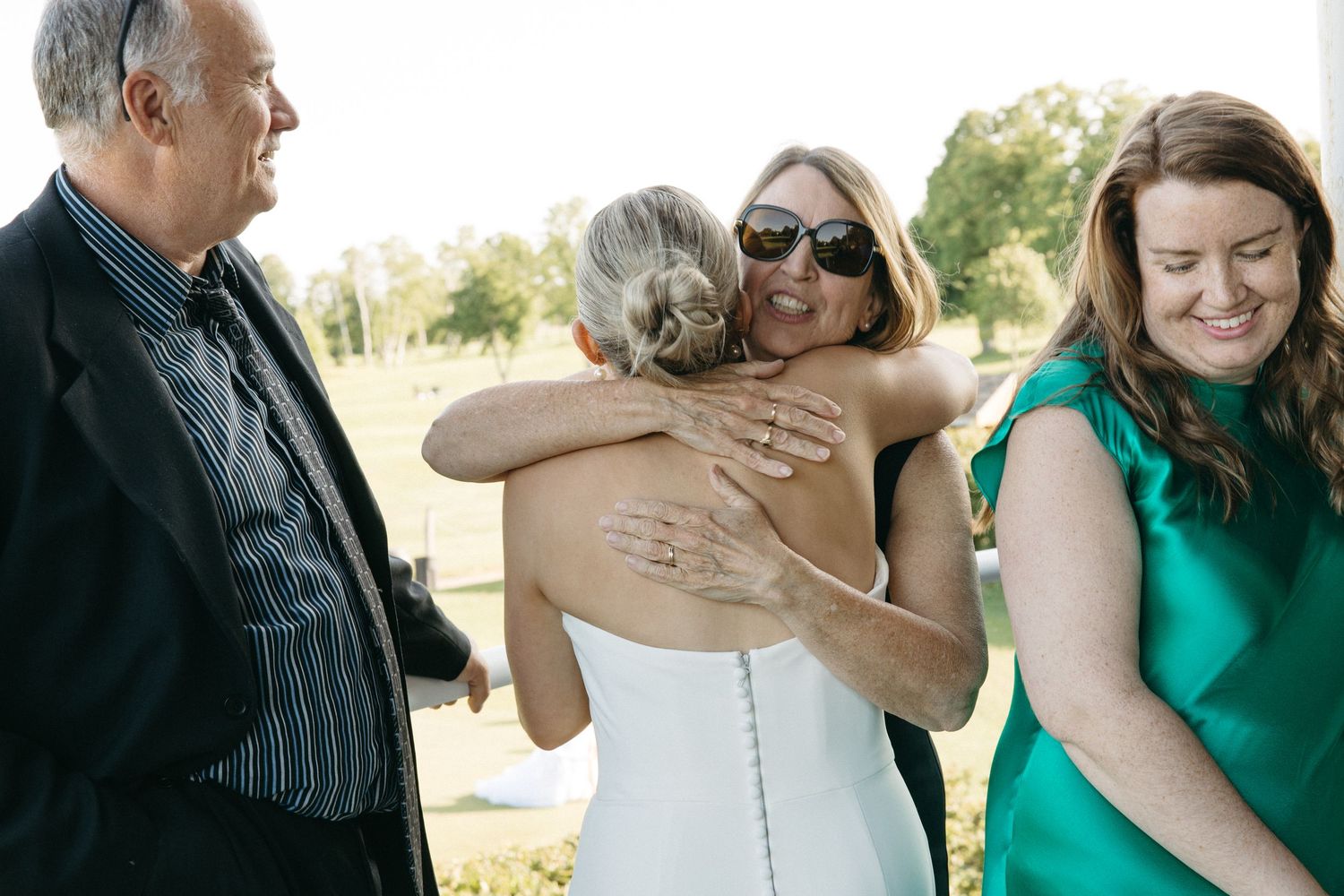 Wedding guests sharing hugs and embraces during outdoor celebration.