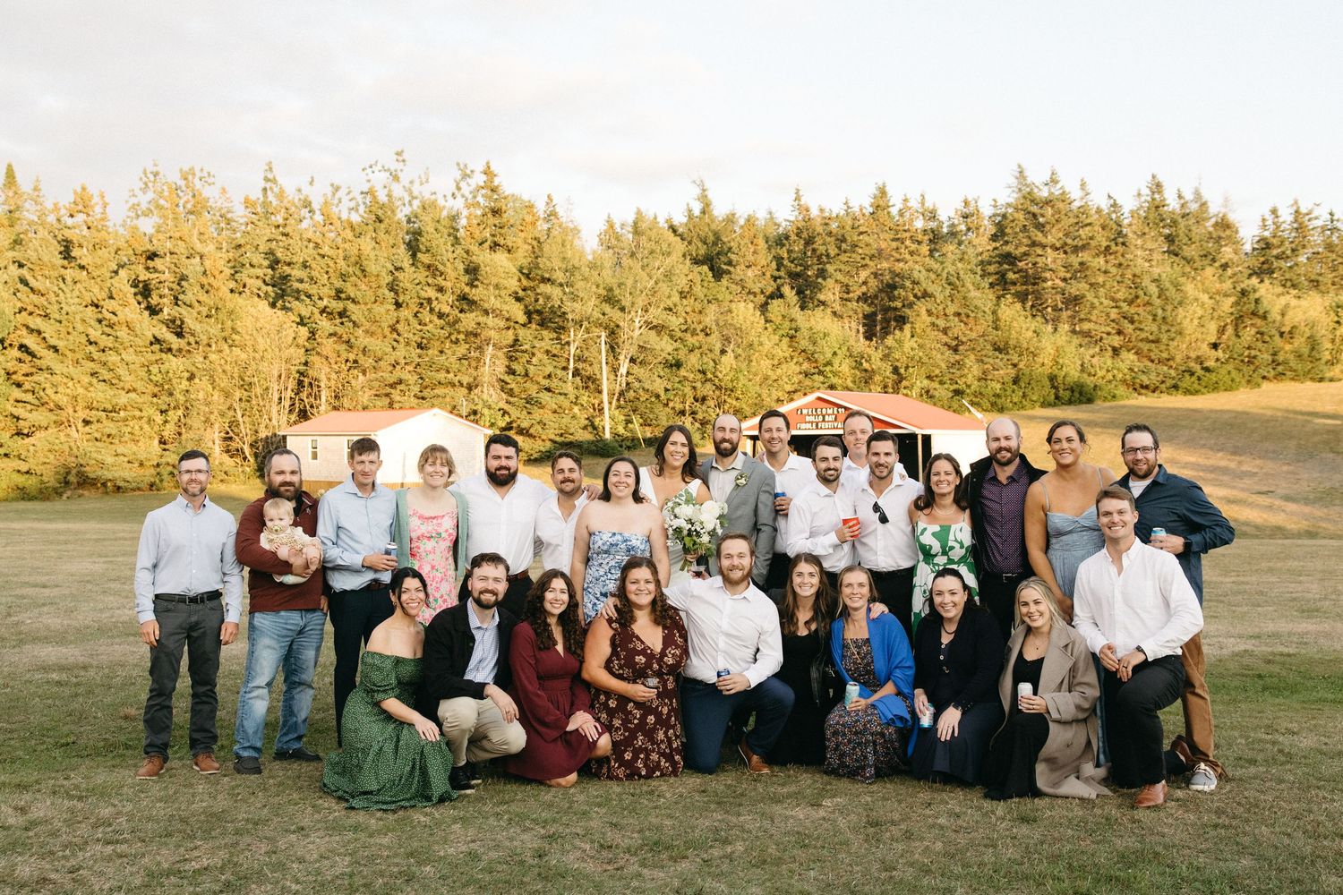 Panoramic shot of wedding guests gathered on a hillside during golden hour.