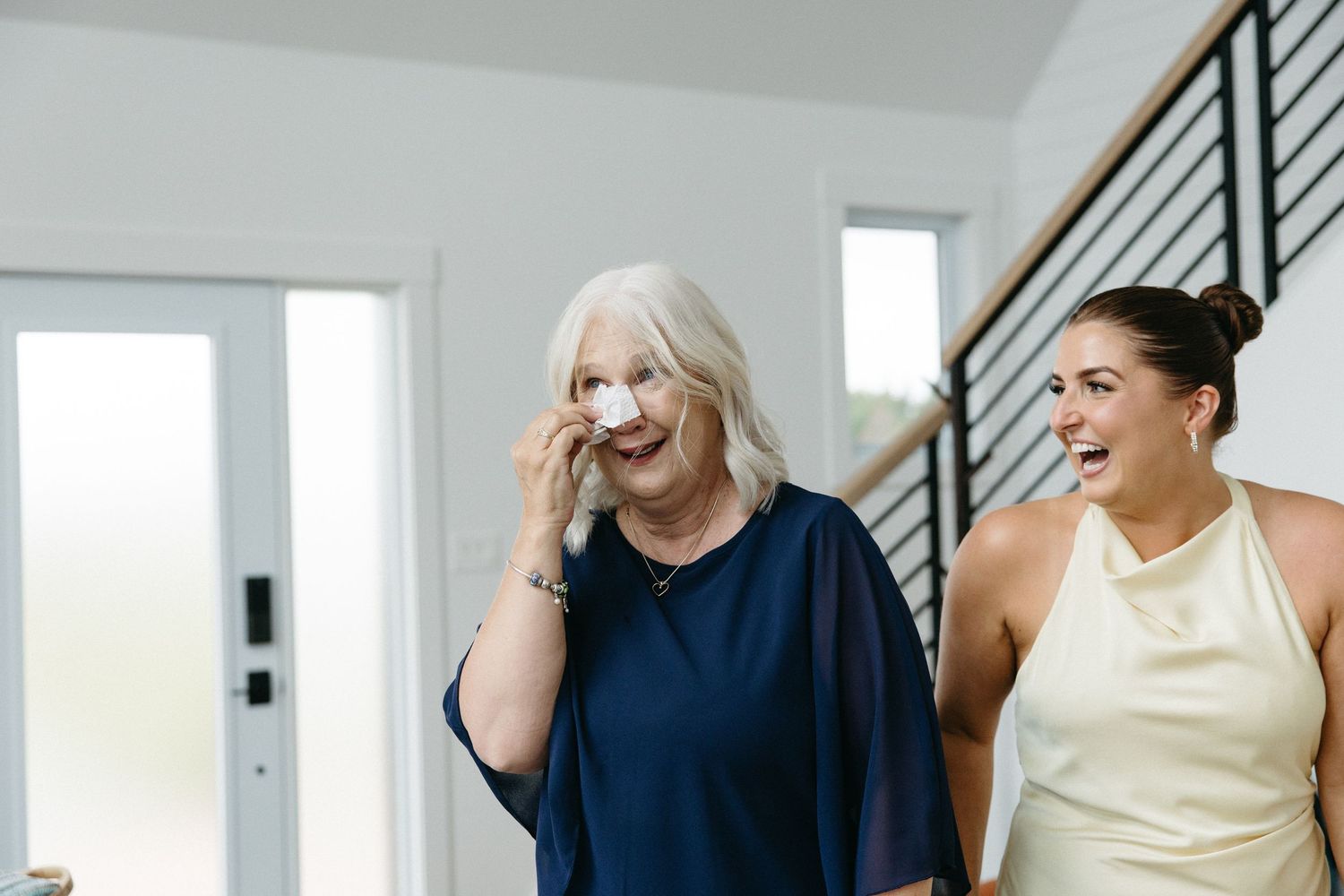 Two people sharing laughter in a modern interior with staircase.