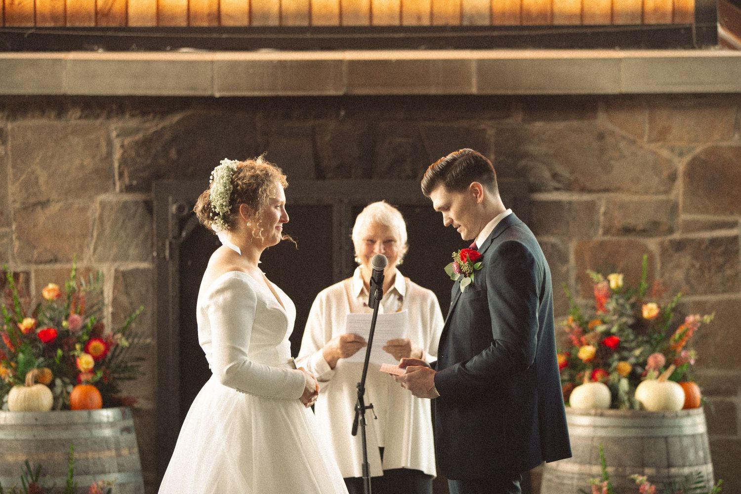 Indoor wedding ceremony with rustic barrel decor and floral arrangements.