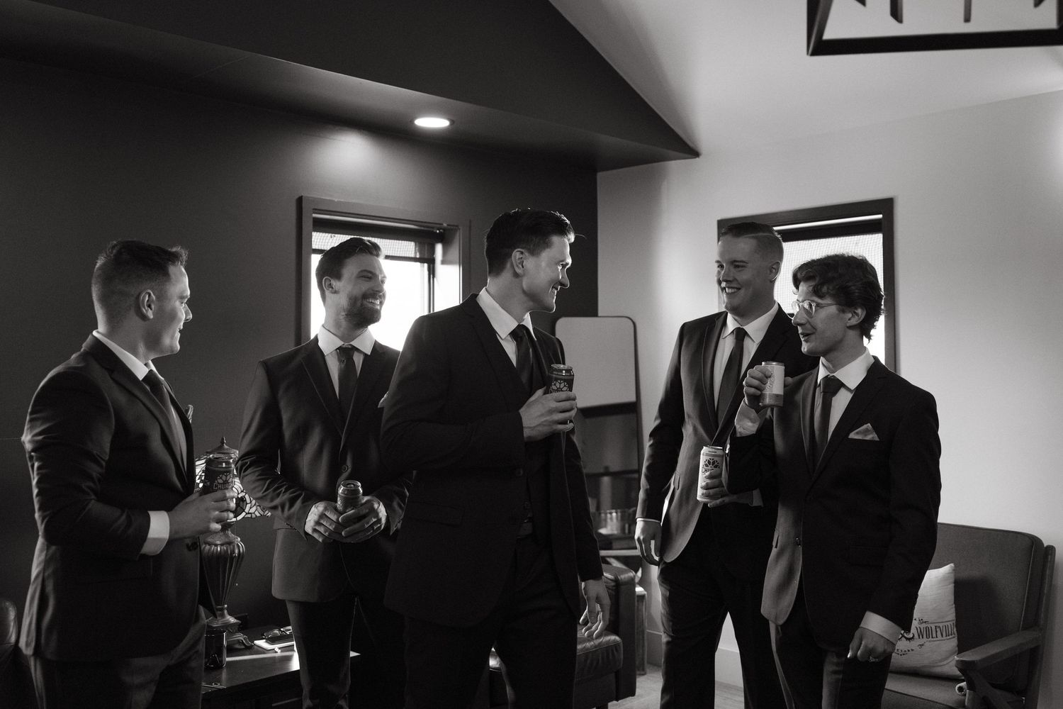 Group of men in suits having drinks and conversation in dark room.