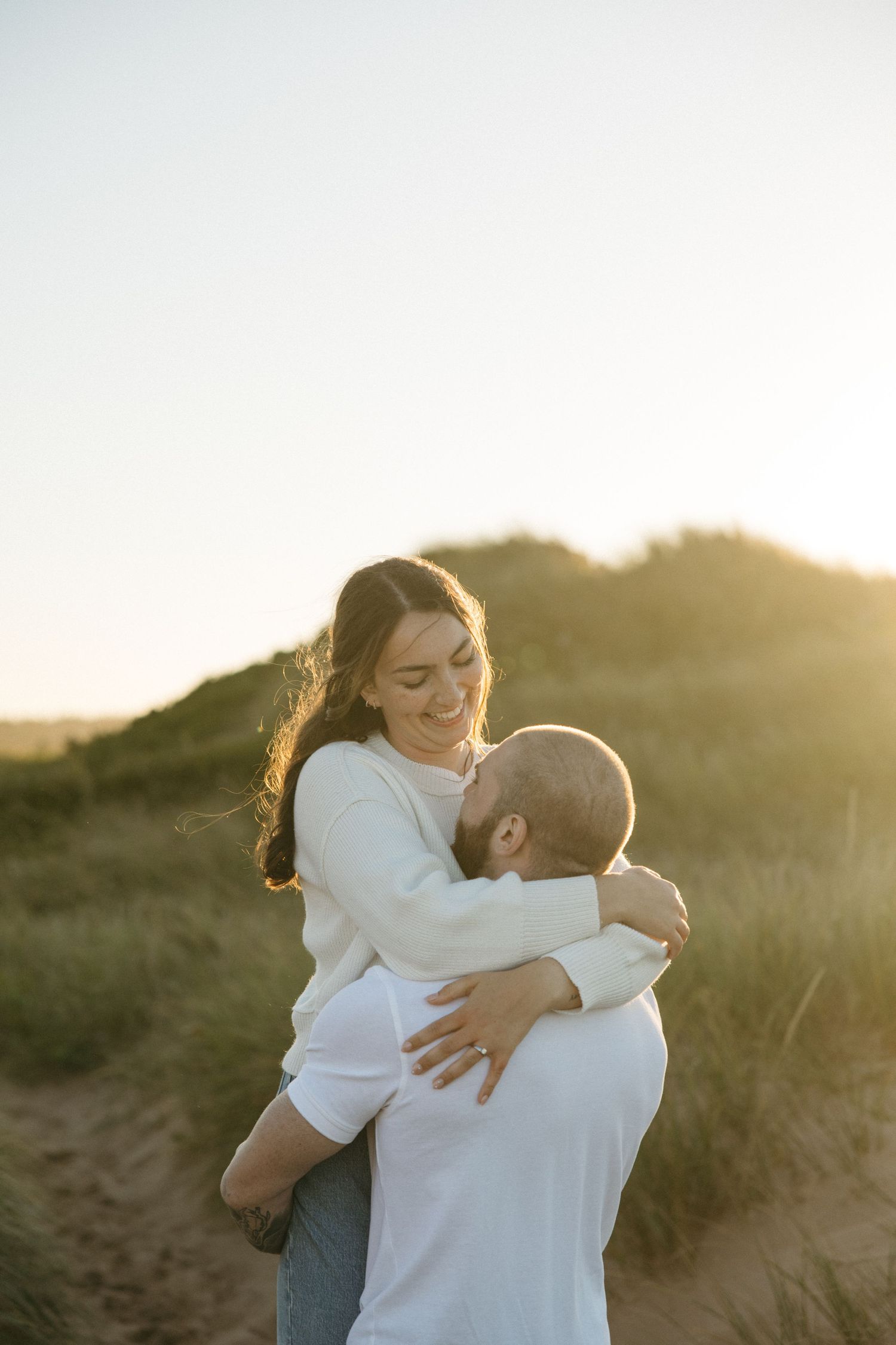 Romantic couple sharing tender moment in warm evening light on sandy dunes.