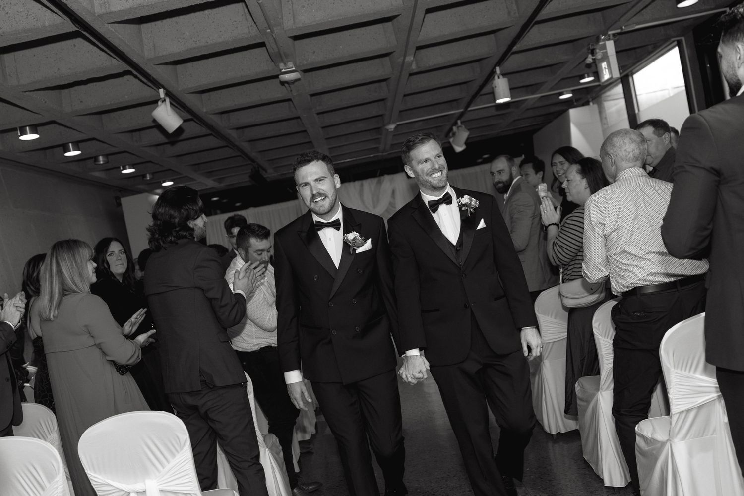 Wedding reception dance floor filled with guests celebrating under dark ceiling lighting.