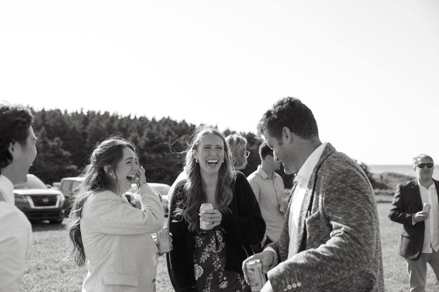 Guests share laughs during an outdoor celebration against a natural backdrop.
