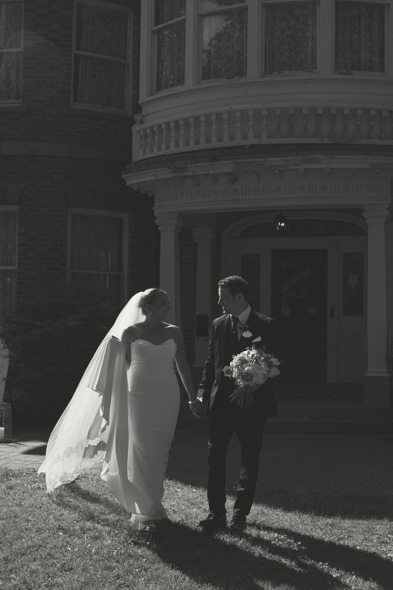 Wedding party silhouettes captured outside a historic brick building in natural light.