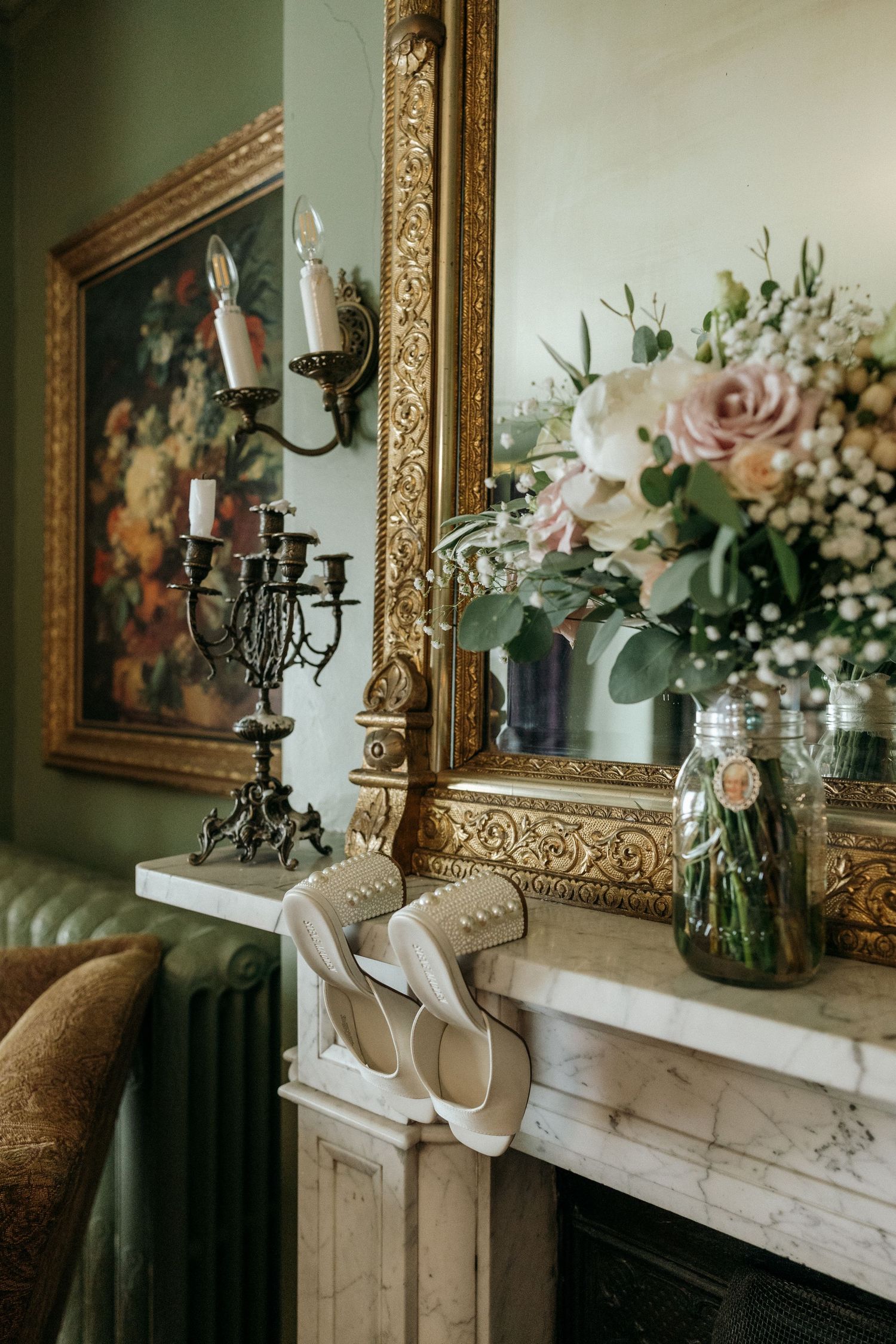 Elegant wedding decor featuring floral arrangements and candelabras on a white mantle with ornate mirror.
