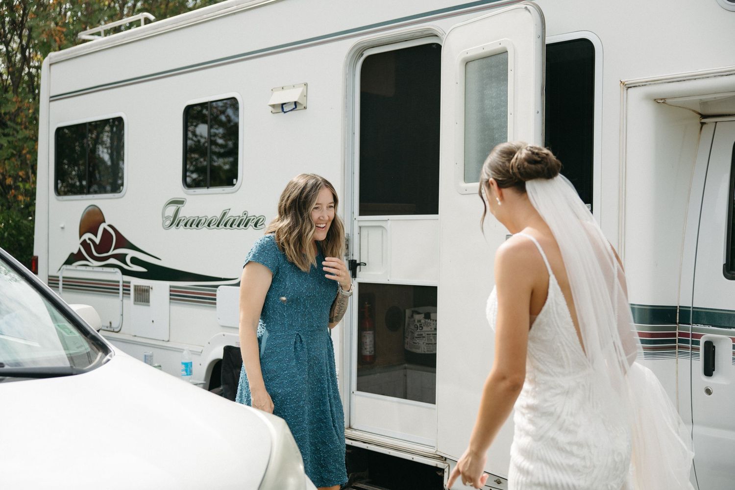 Wedding preparation scene outside RVs and trailers in a casual outdoor setting.