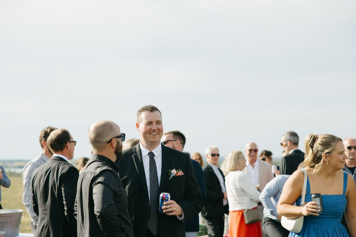 Wedding guests socializing during an outdoor reception under clear skies.