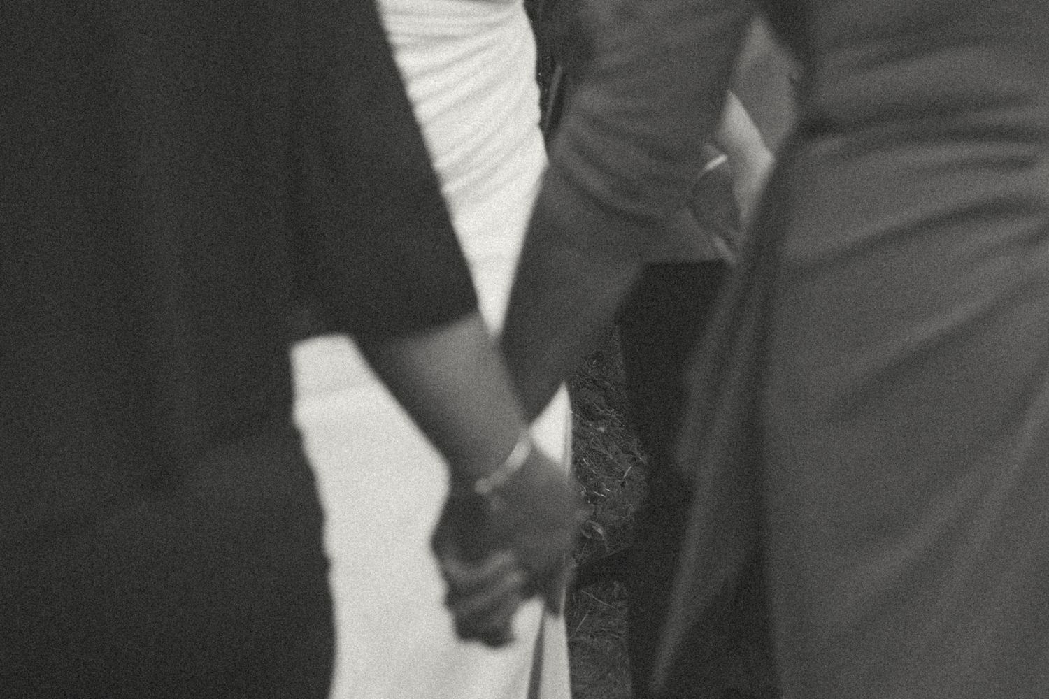Black and white photo showing hands signing a document on a wooden table.