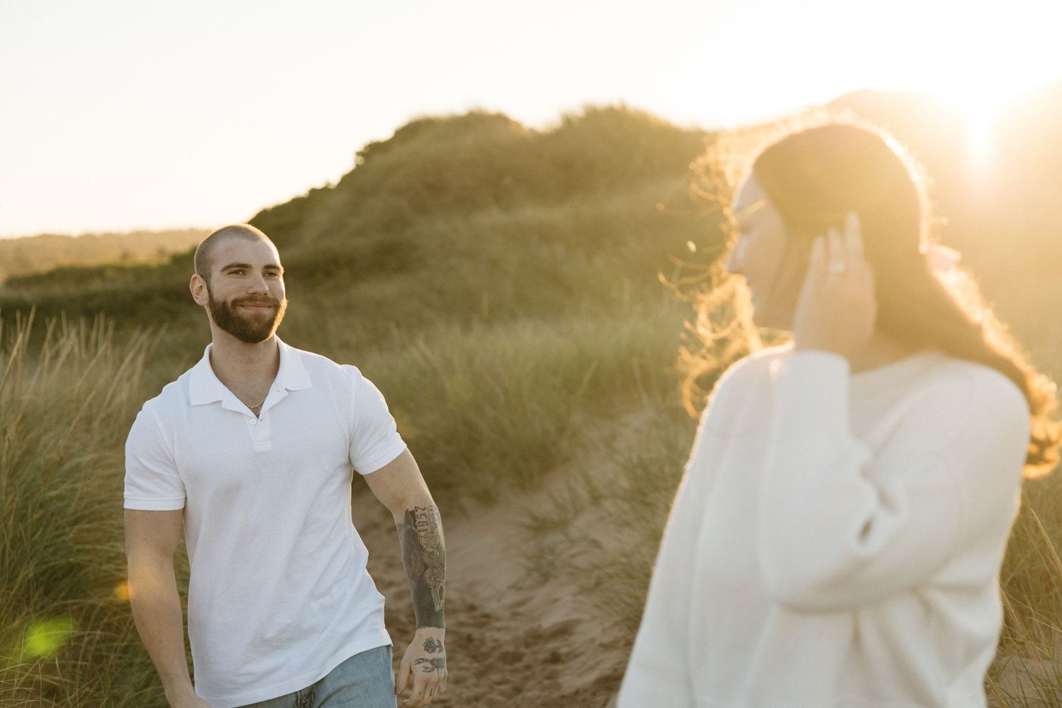 Couple shares intimate conversation during golden hour photoshoot in natural setting.