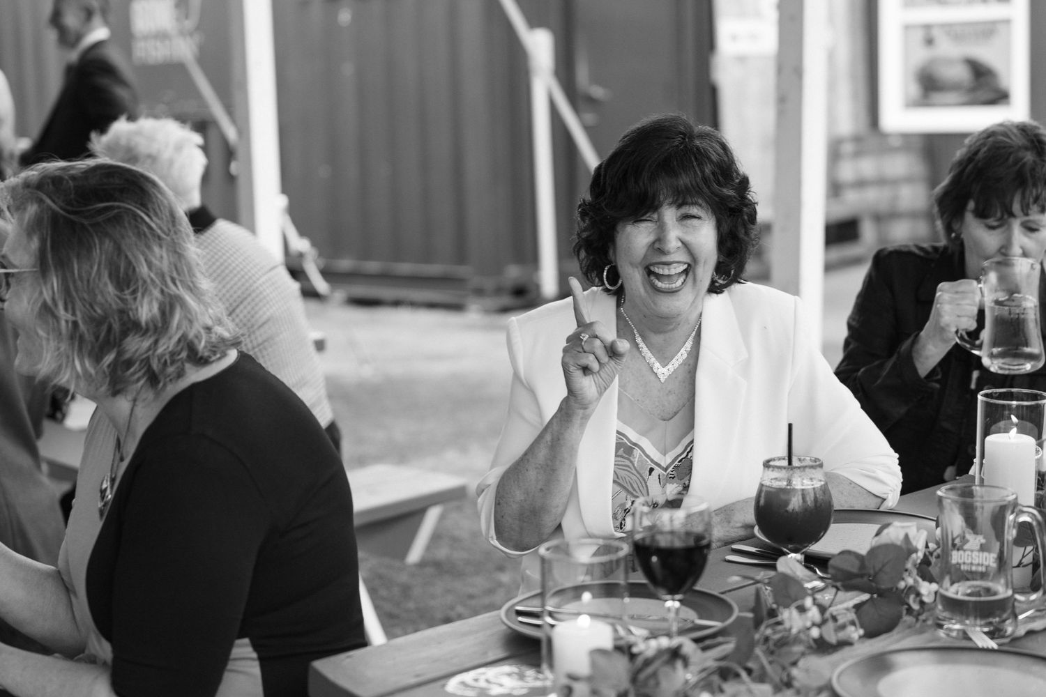 Wedding reception guests enjoying drinks and conversation at tables.