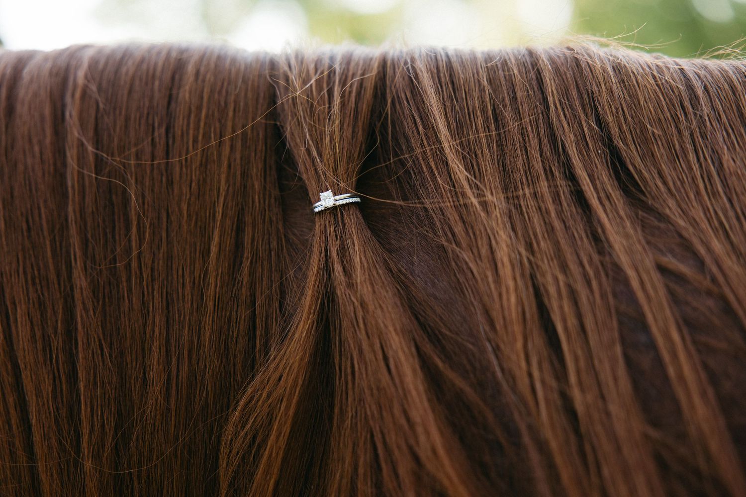 Close-up of auburn hair with a delicate silver star hair pin accessory nestled in silky strands.