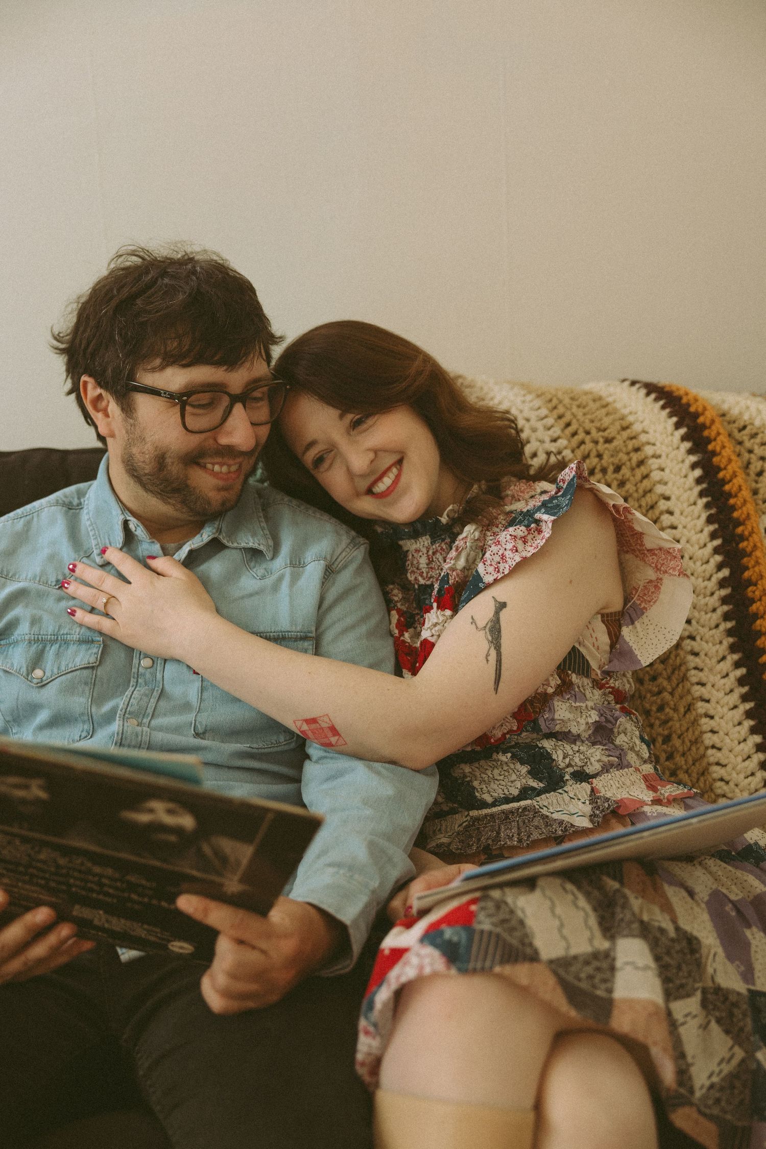 Couple shares tender moment while reading together on vintage couch.