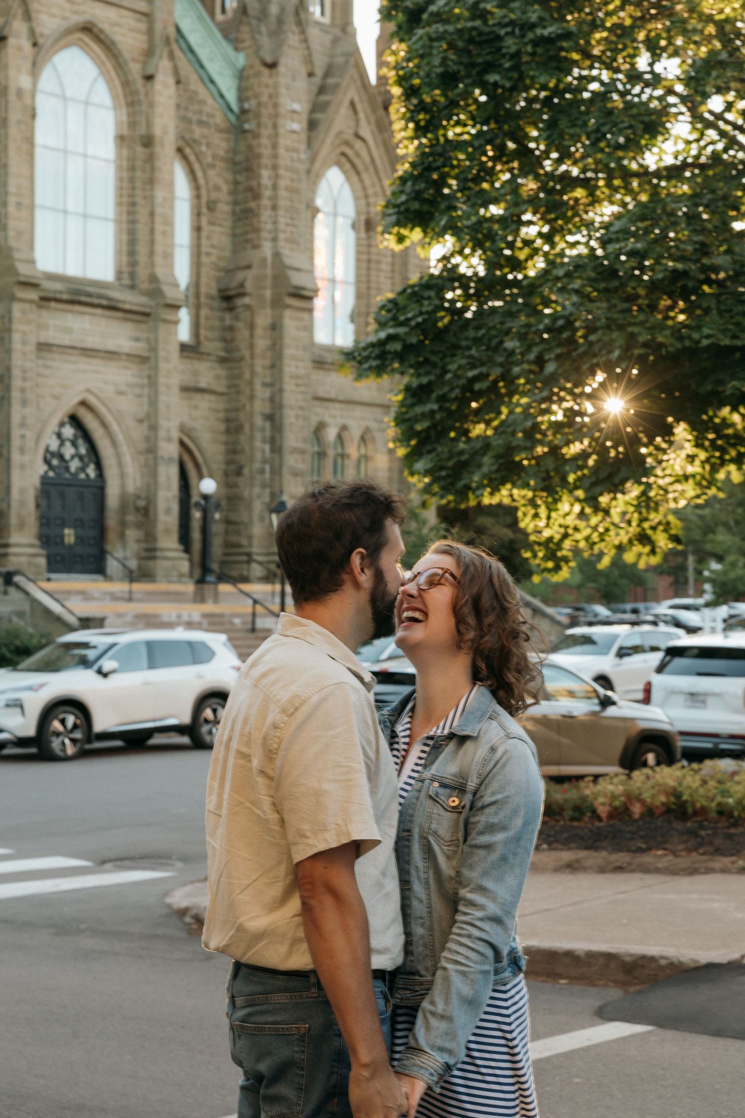 A romantic moment shared between a couple outside a historic stone church at sunset.