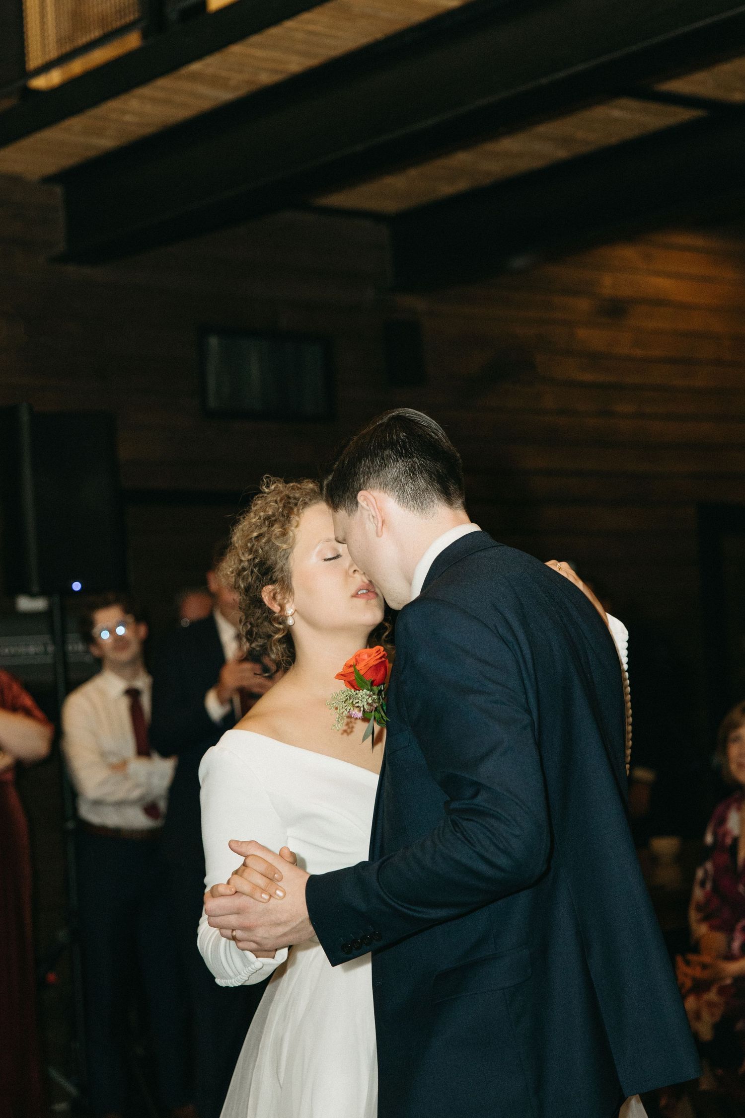 Couple shares their first dance in a rustic venue with wooden beam ceiling.