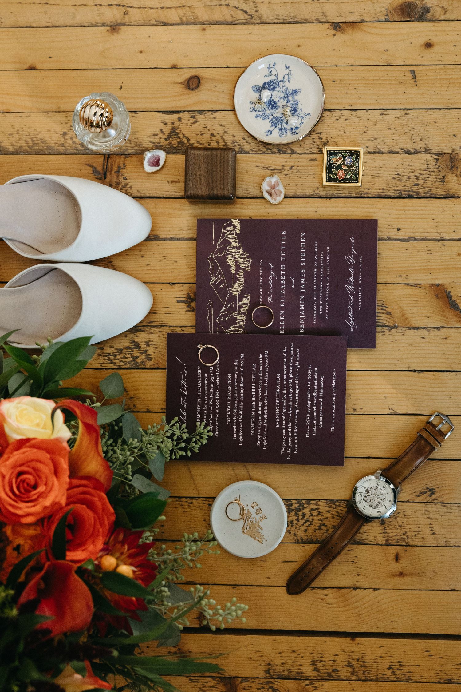 Wedding menus and decorative elements arranged on rustic wooden planks with orange roses.