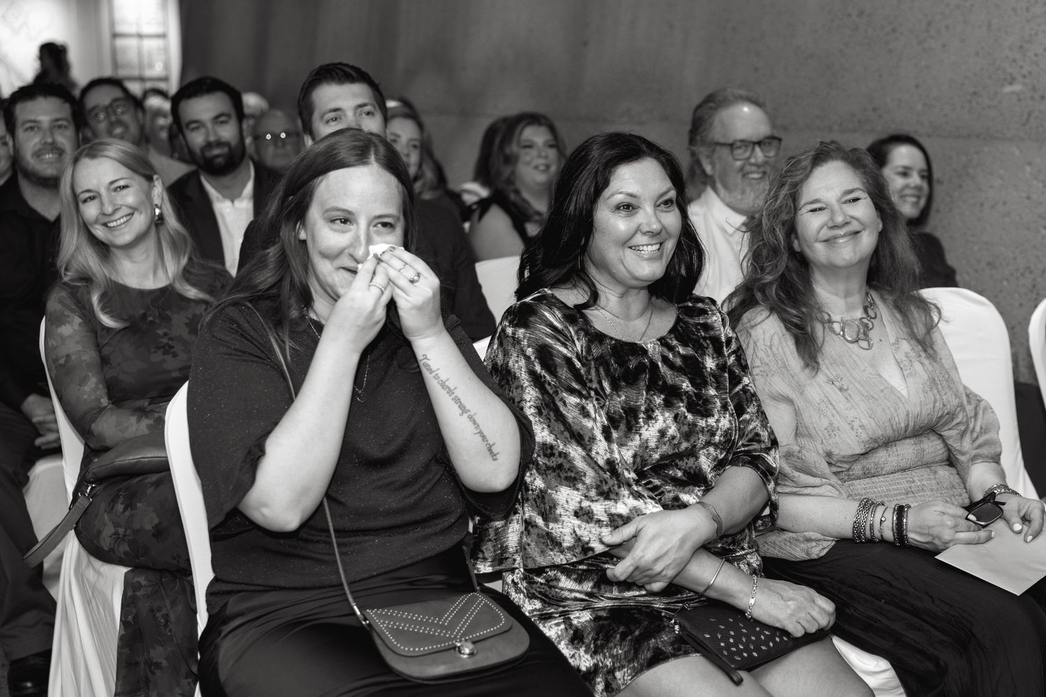 Black and white photo of audience members showing emotional reactions during an event.