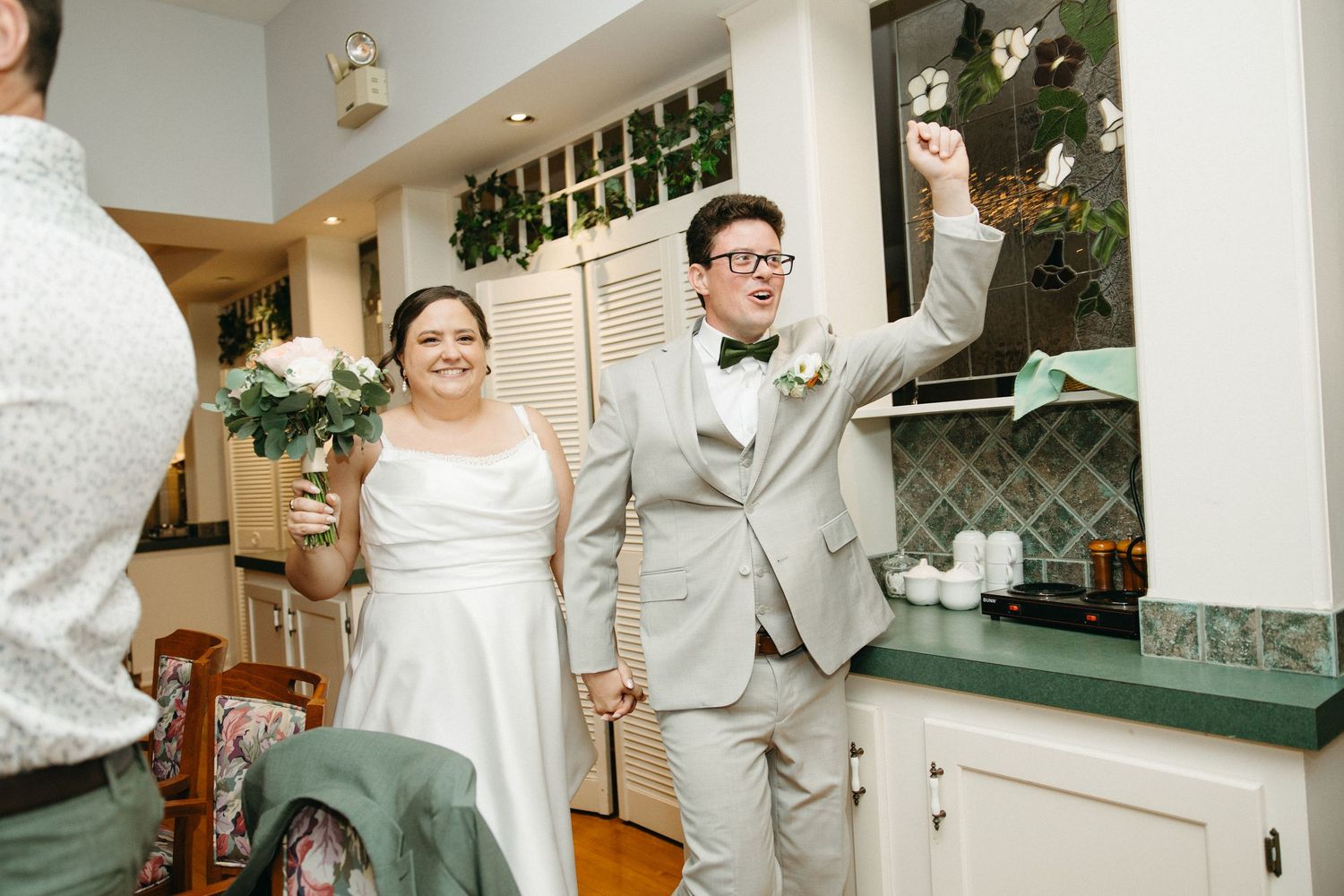 Smiling bride and groom making a grand entrance into their wedding reception holding bouquet.