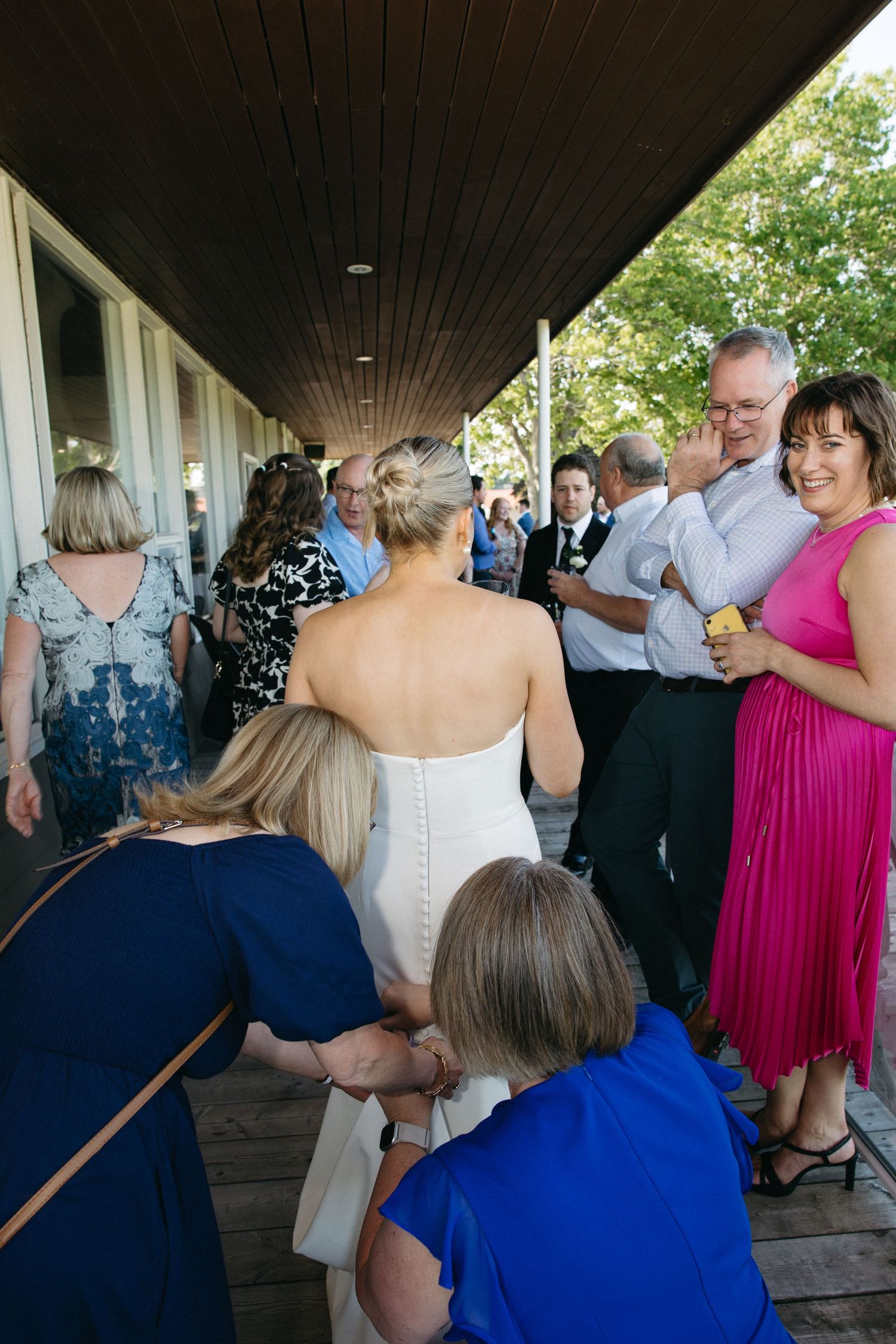Wedding guests in formal attire dancing and mingling under a covered patio.