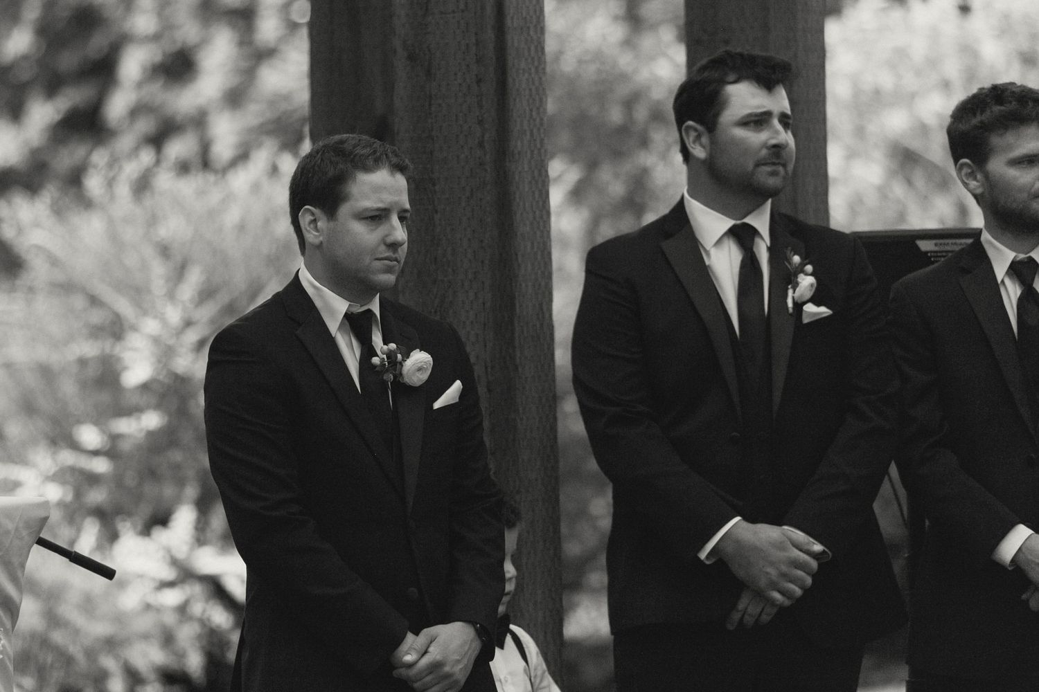 Wedding party in formal black suits standing in a line during ceremony.