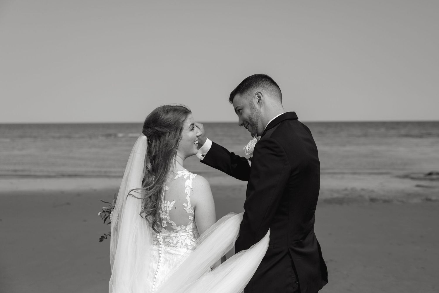 Black and white romantic beach portraits with waves crashing in background.