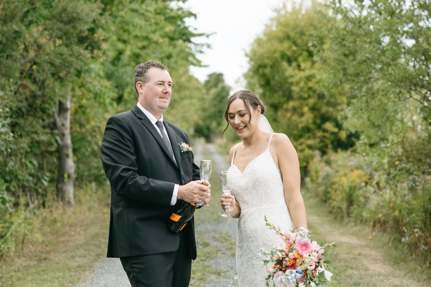 Wedding couple shares romantic moments along tree-lined path.