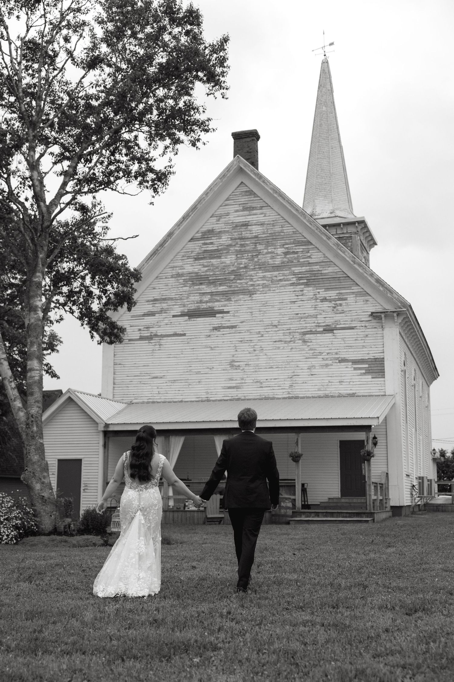 Black and white photos of newlyweds walking near a historic white church building.