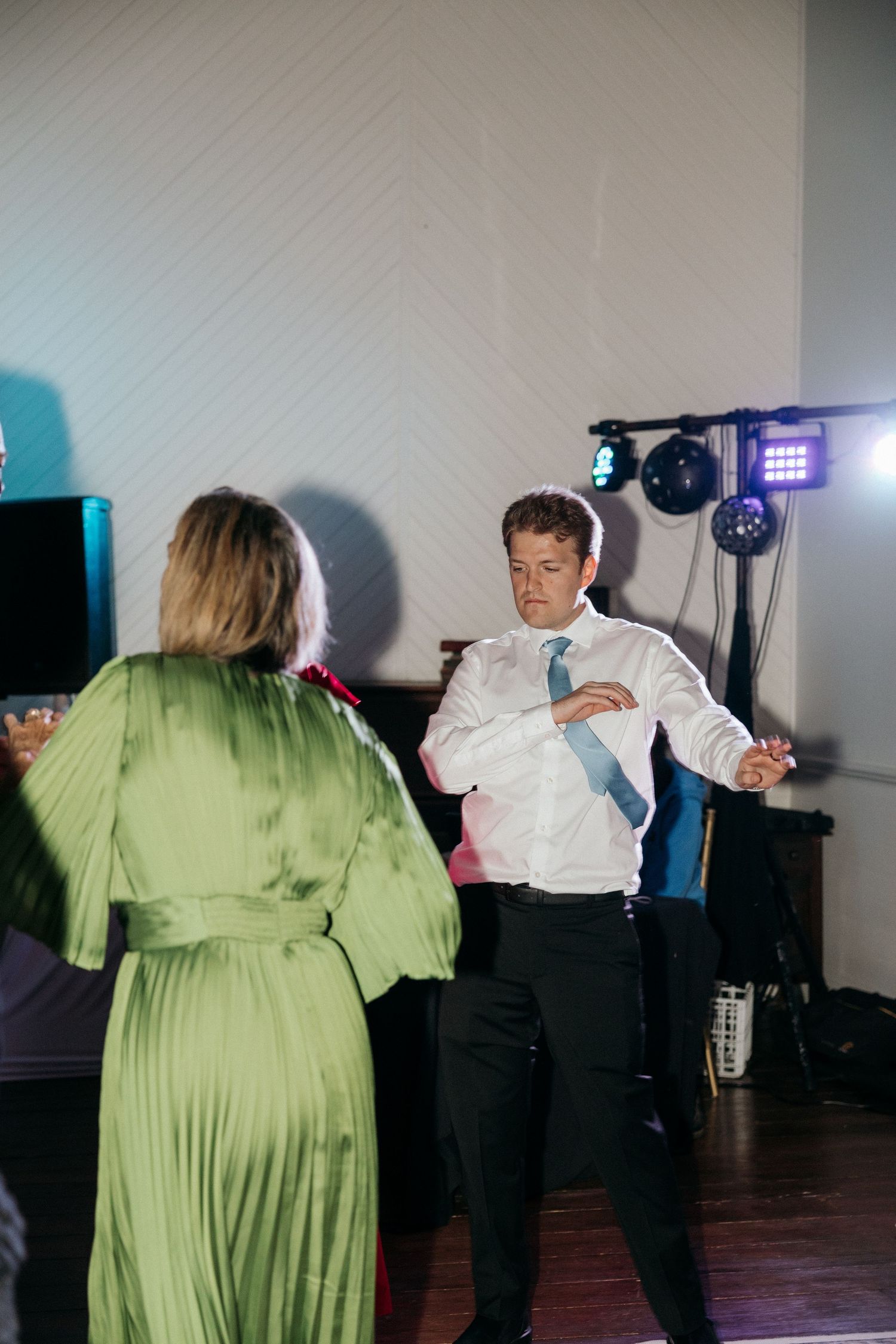 A couple dancing at a reception with a person in a flowing green dress.