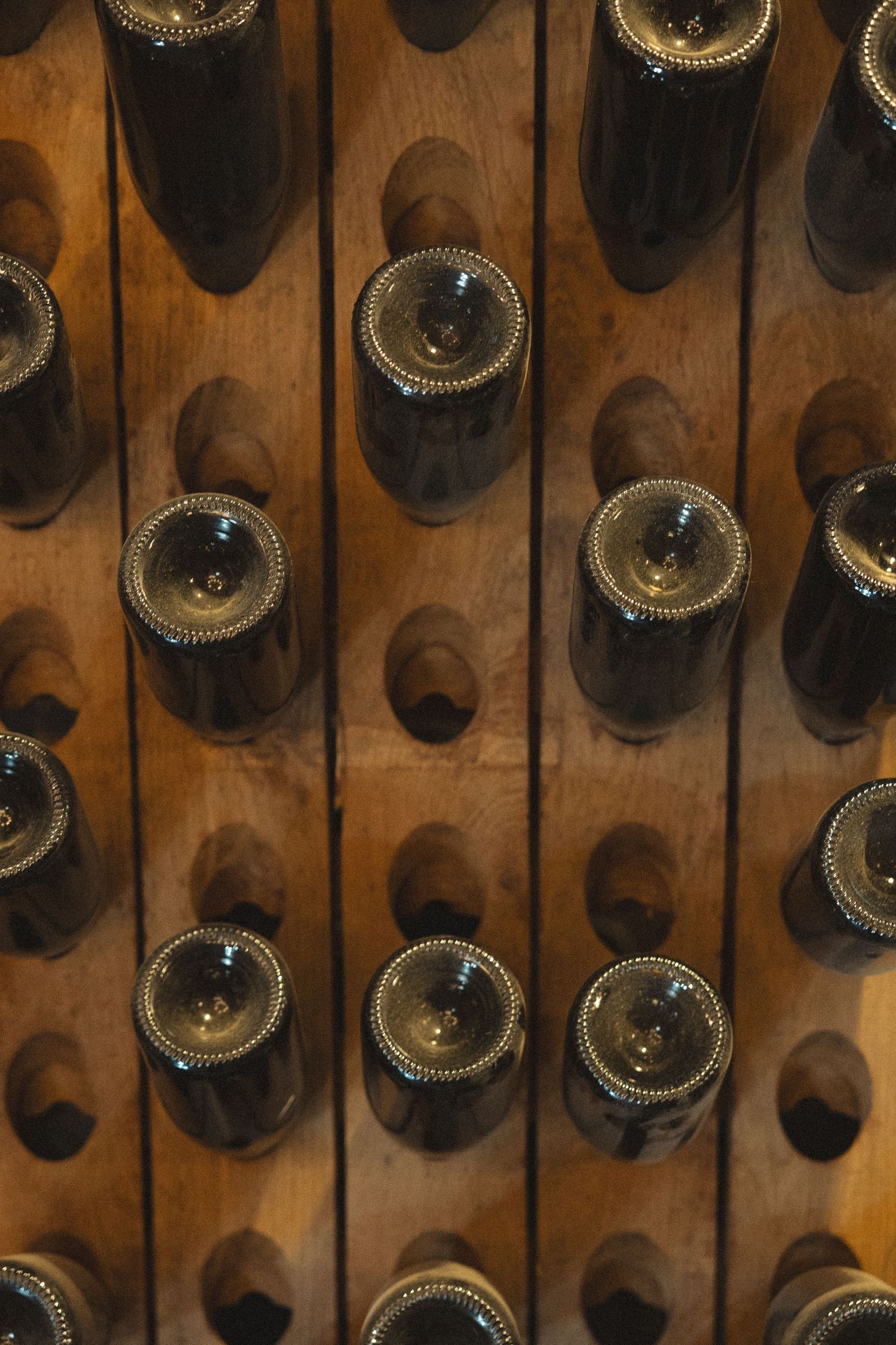 Close-up of wine bottles arranged in wooden rack storage.