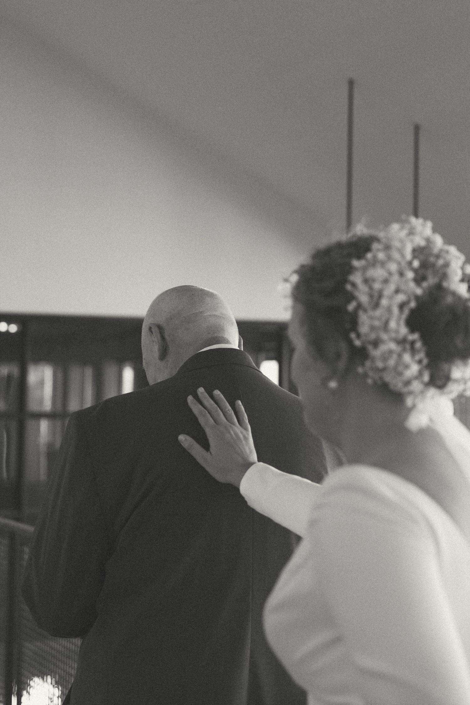 An emotional moment between a bride and someone in formal attire during a wedding ceremony.