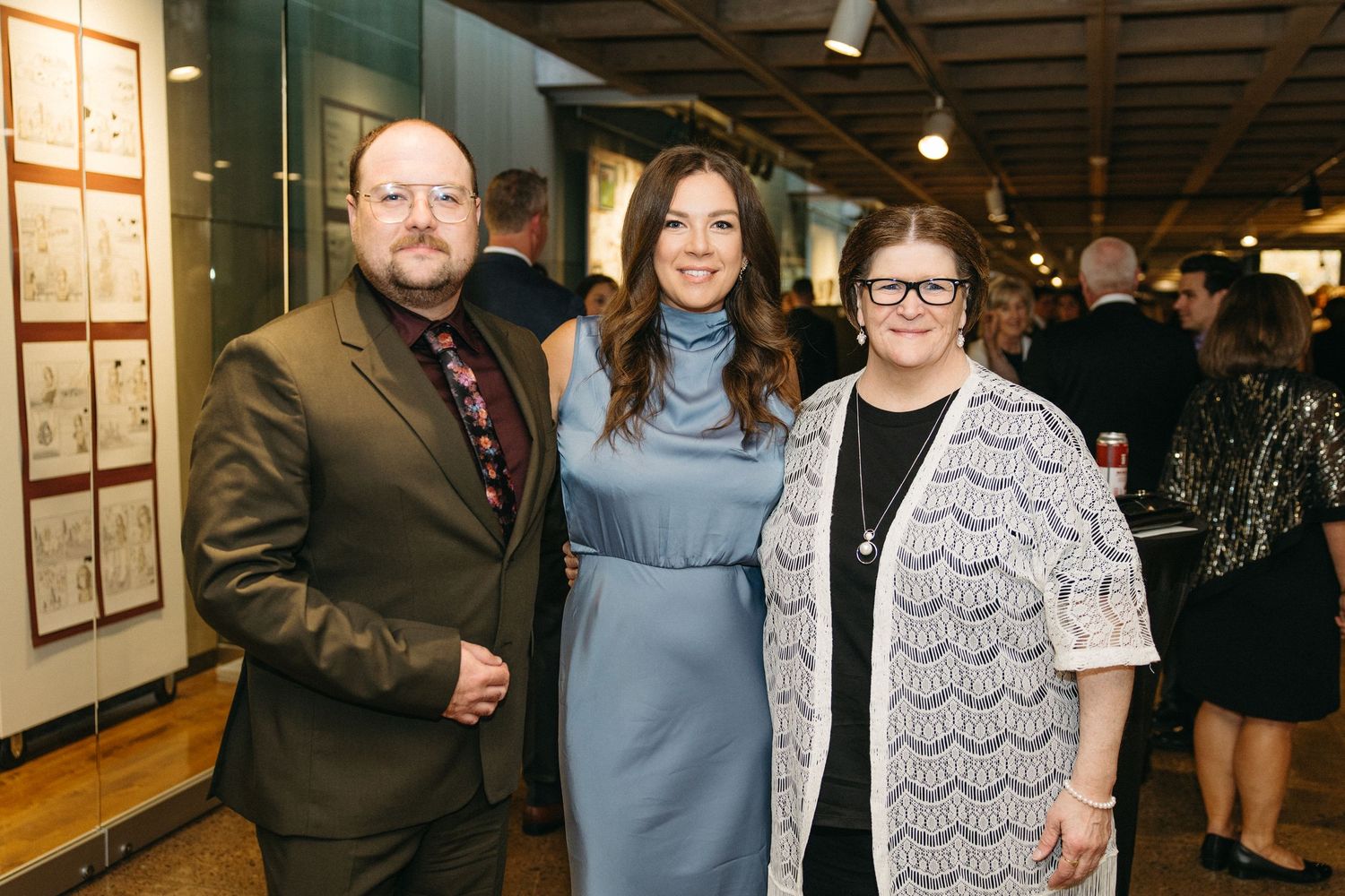 Event attendees in formal wear posing together at an indoor venue.