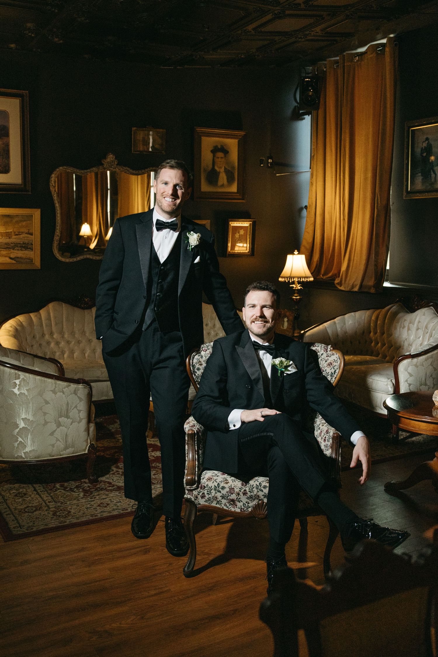 Formal portrait session in an elegant lounge featuring people in tuxedos against vintage decor.