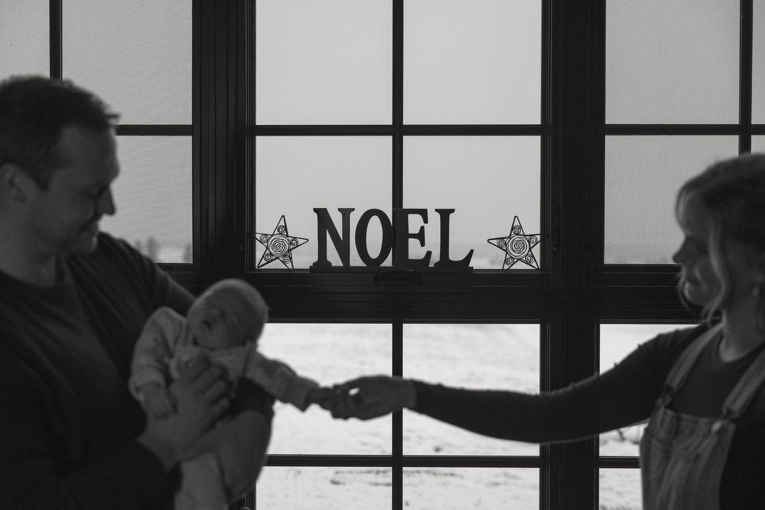 Black and white silhouettes of a family against bright windows in a cozy indoor setting.