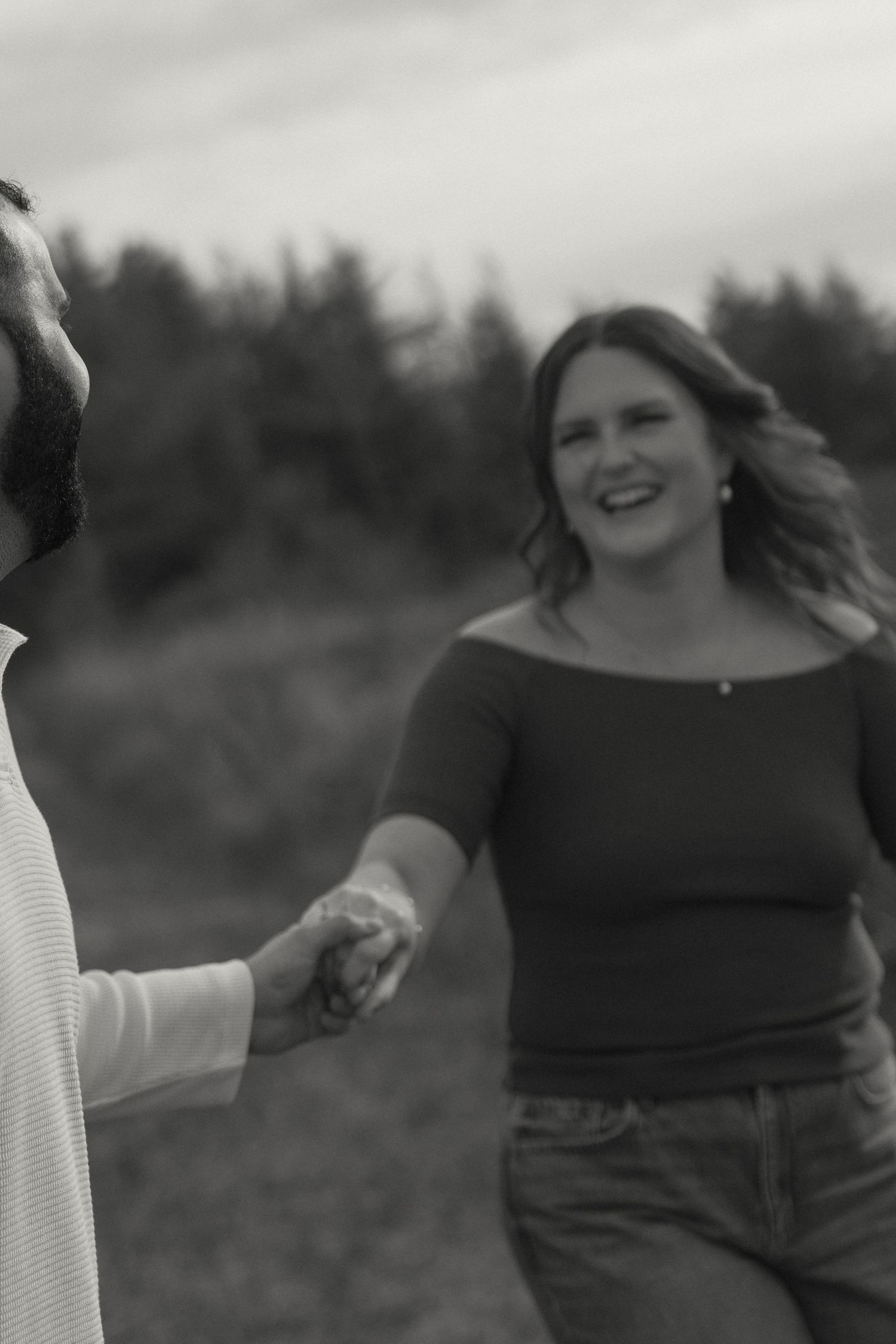 Black and white photos of a joyful couple dancing and laughing together in a field.