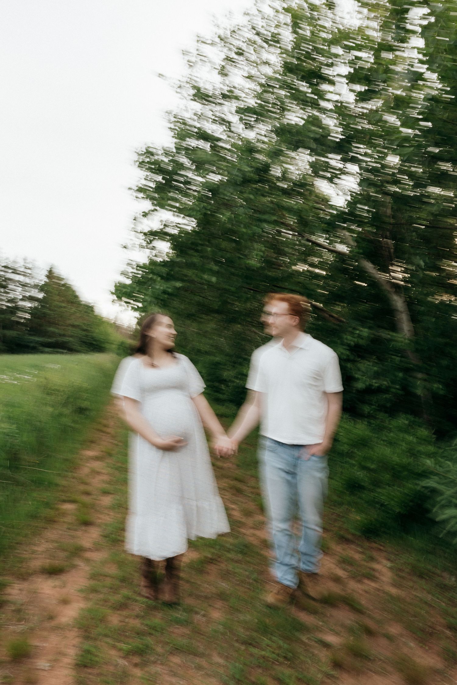 A couple walking hand in hand through a wooded area in motion blur effect.
