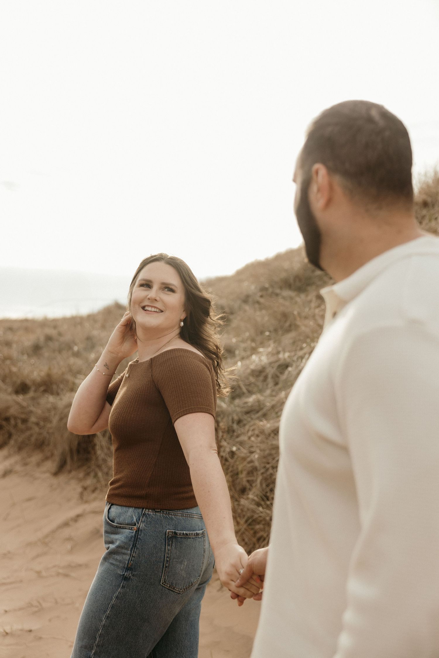 Candid moment captured between two people on sandy beach dunes.