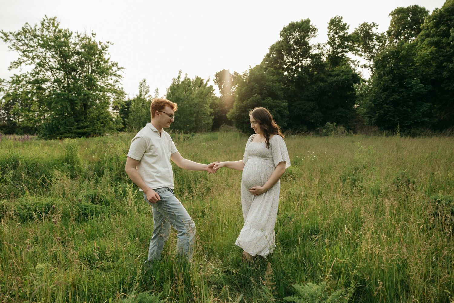 Couple enjoying a playful moment together in a sunlit meadow.