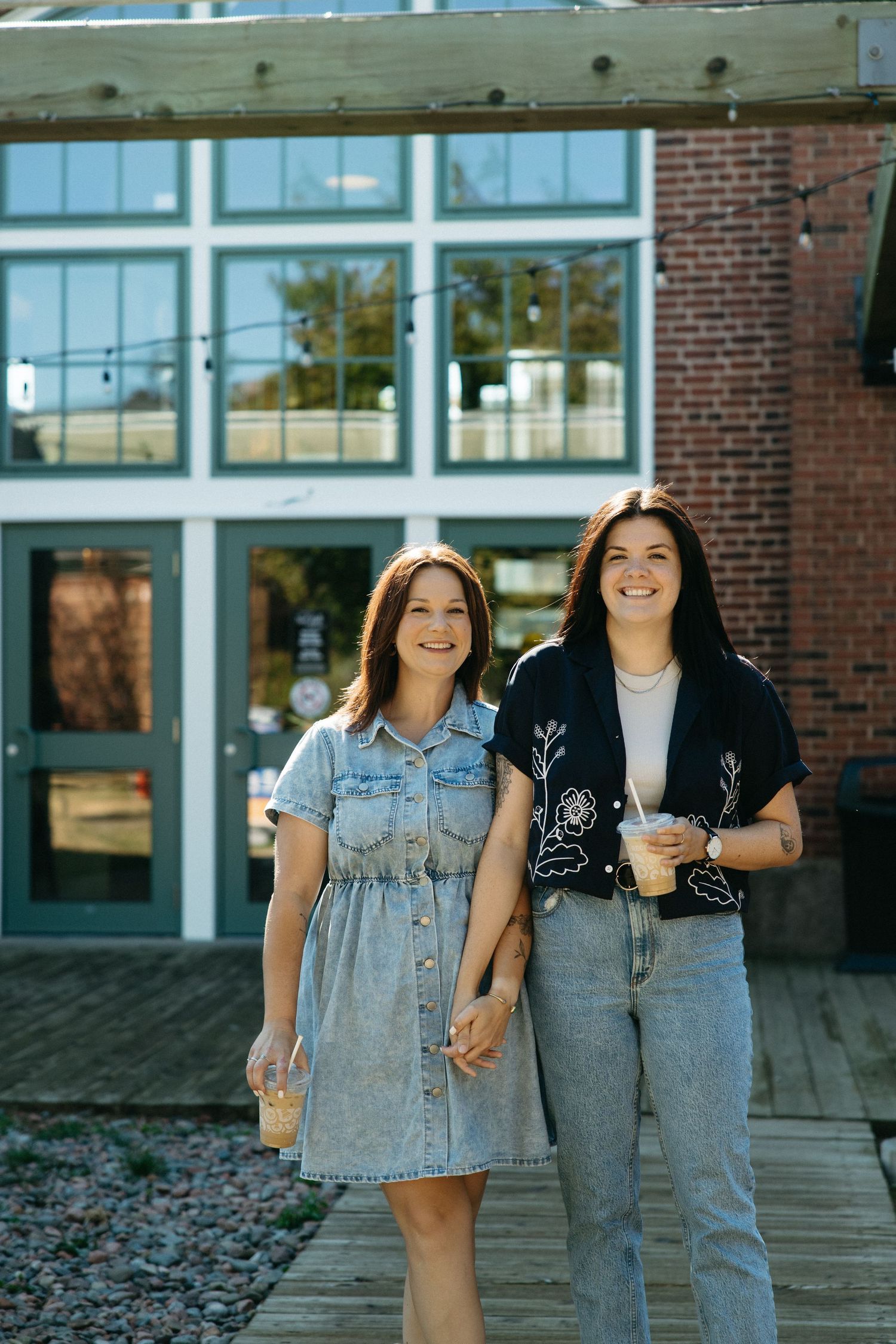 Happy couple walking together outside a brick building with large windows.
