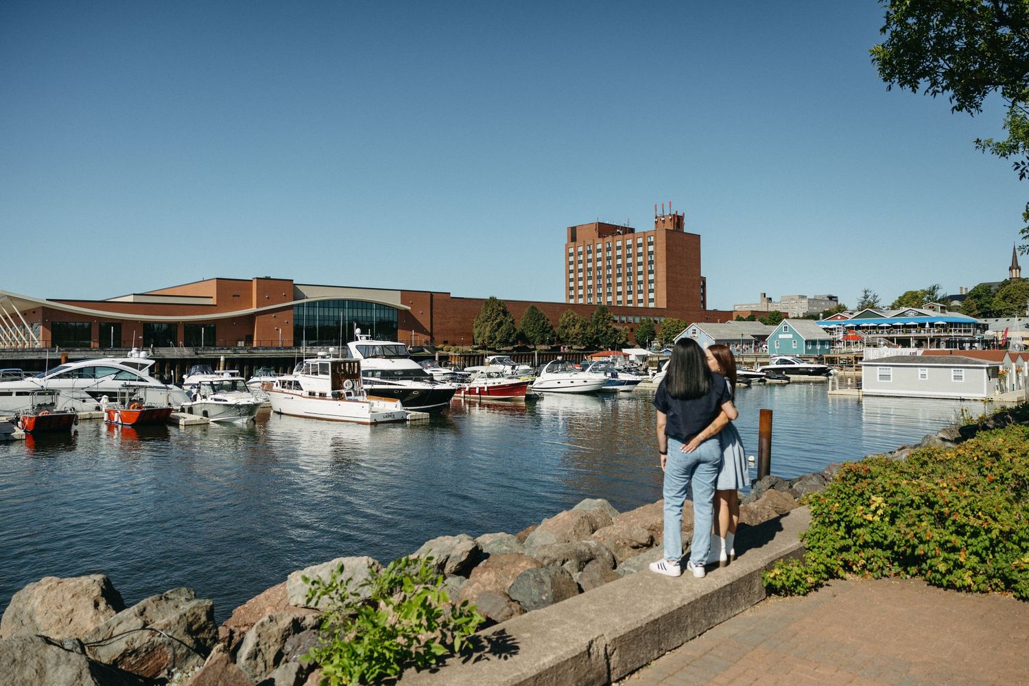 Person looking out at a marina with boats and buildings visible in the background.
