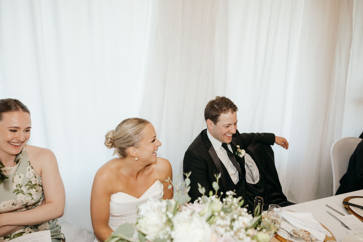 Wedding party members seated at tables during a reception celebration.