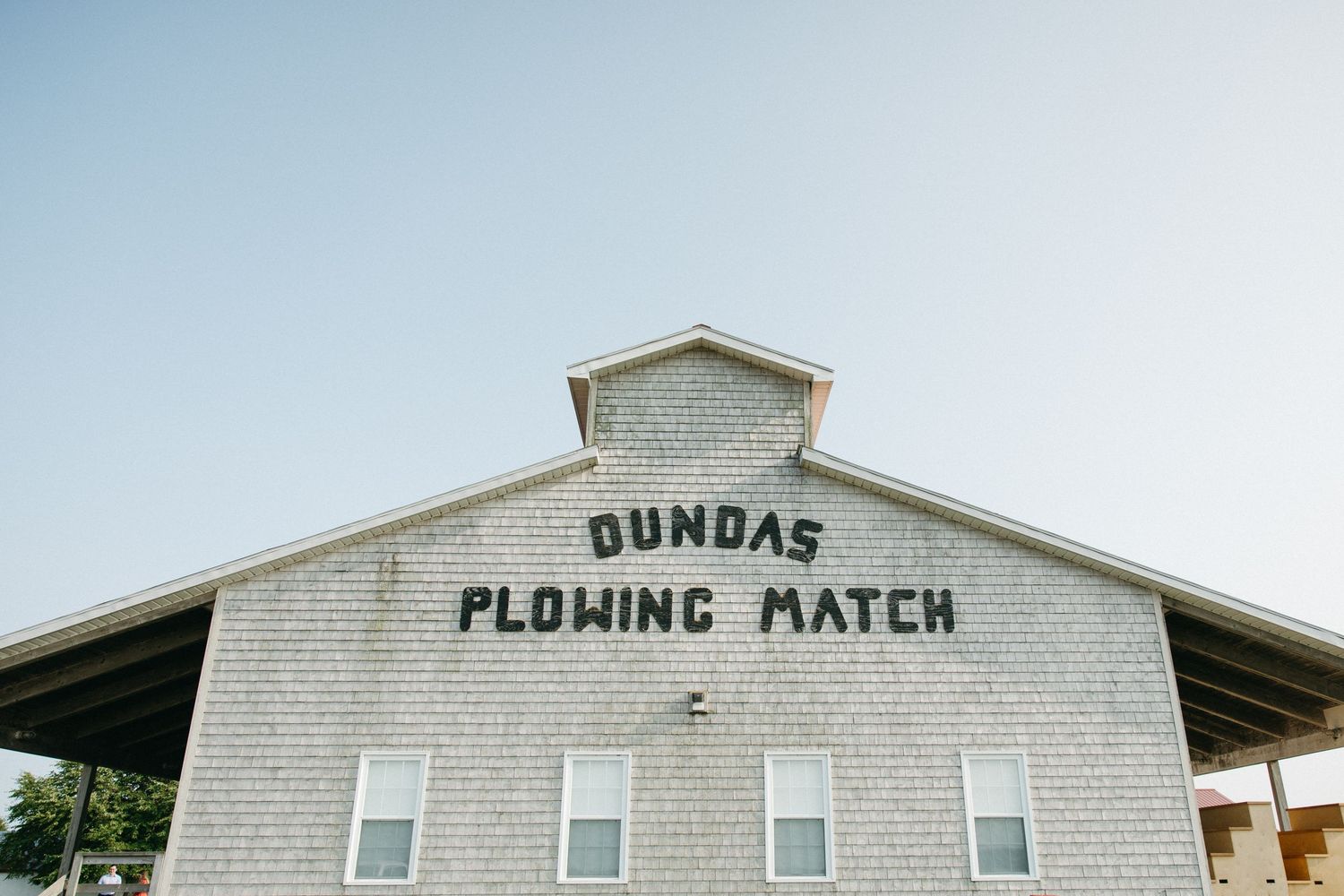 White building exterior with 'Dundas Plowing Match' text on facade against blue sky.