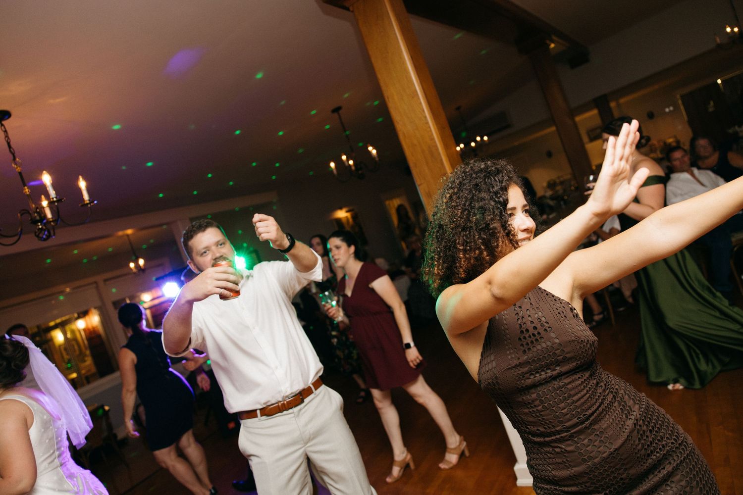 Guests dancing energetically on the dance floor at a lively wedding reception celebration.