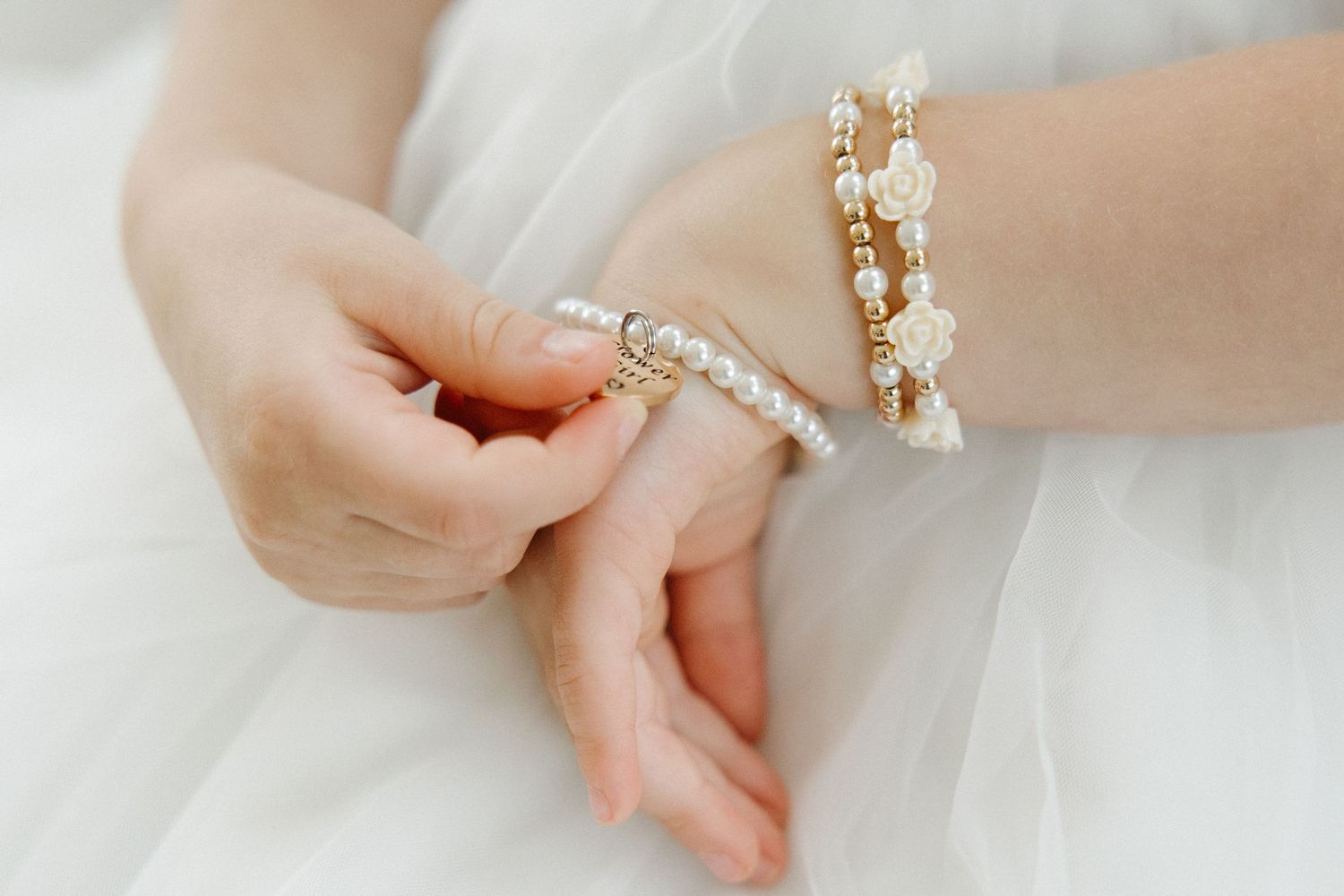 Close-up of delicate pearl and crystal bridal jewelry on hands.