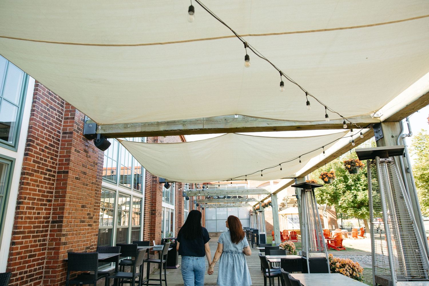 String lights hanging above an outdoor patio area near brick building walls.
