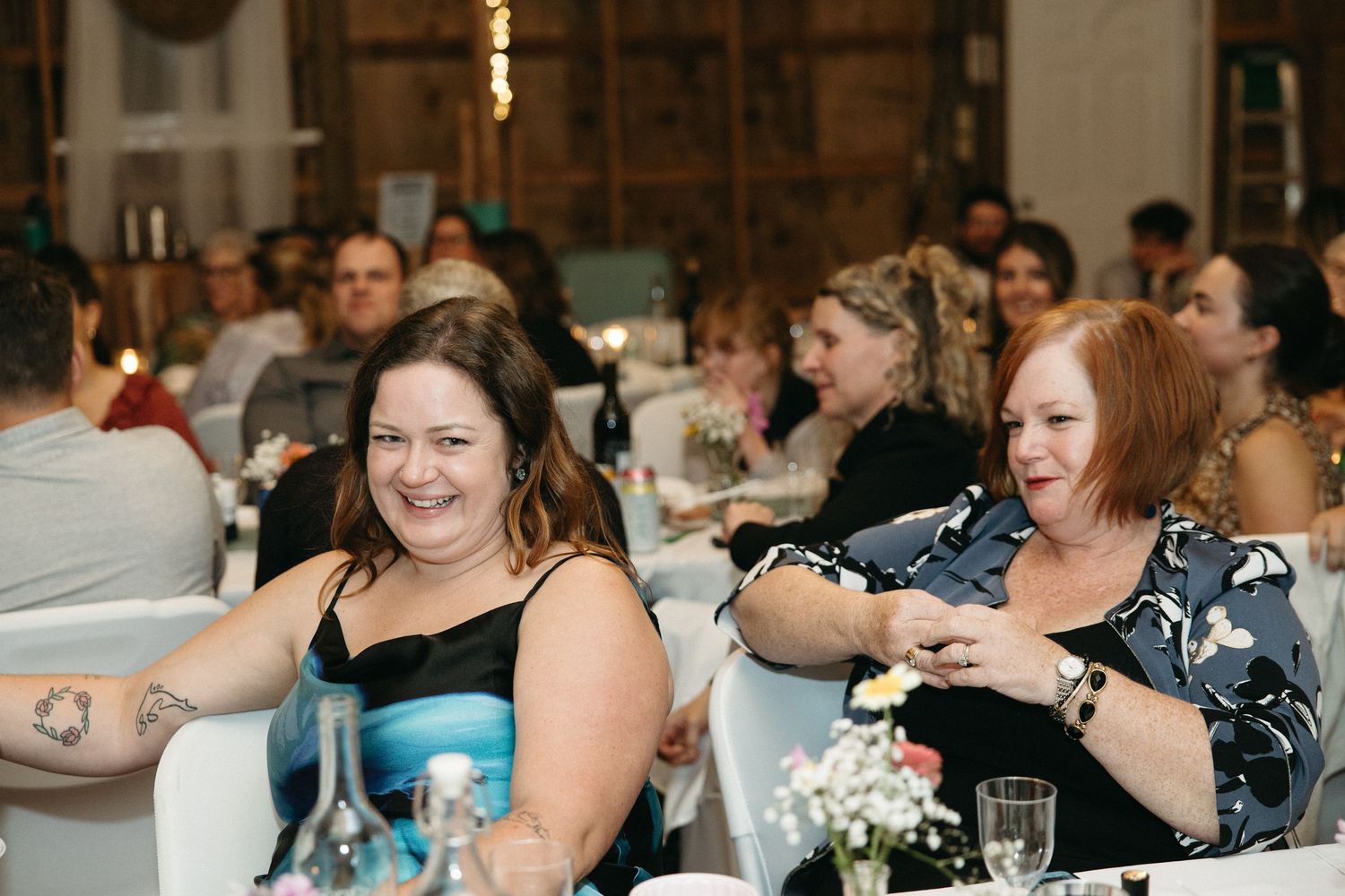 Wedding reception guests enjoying dinner and conversation at tables.